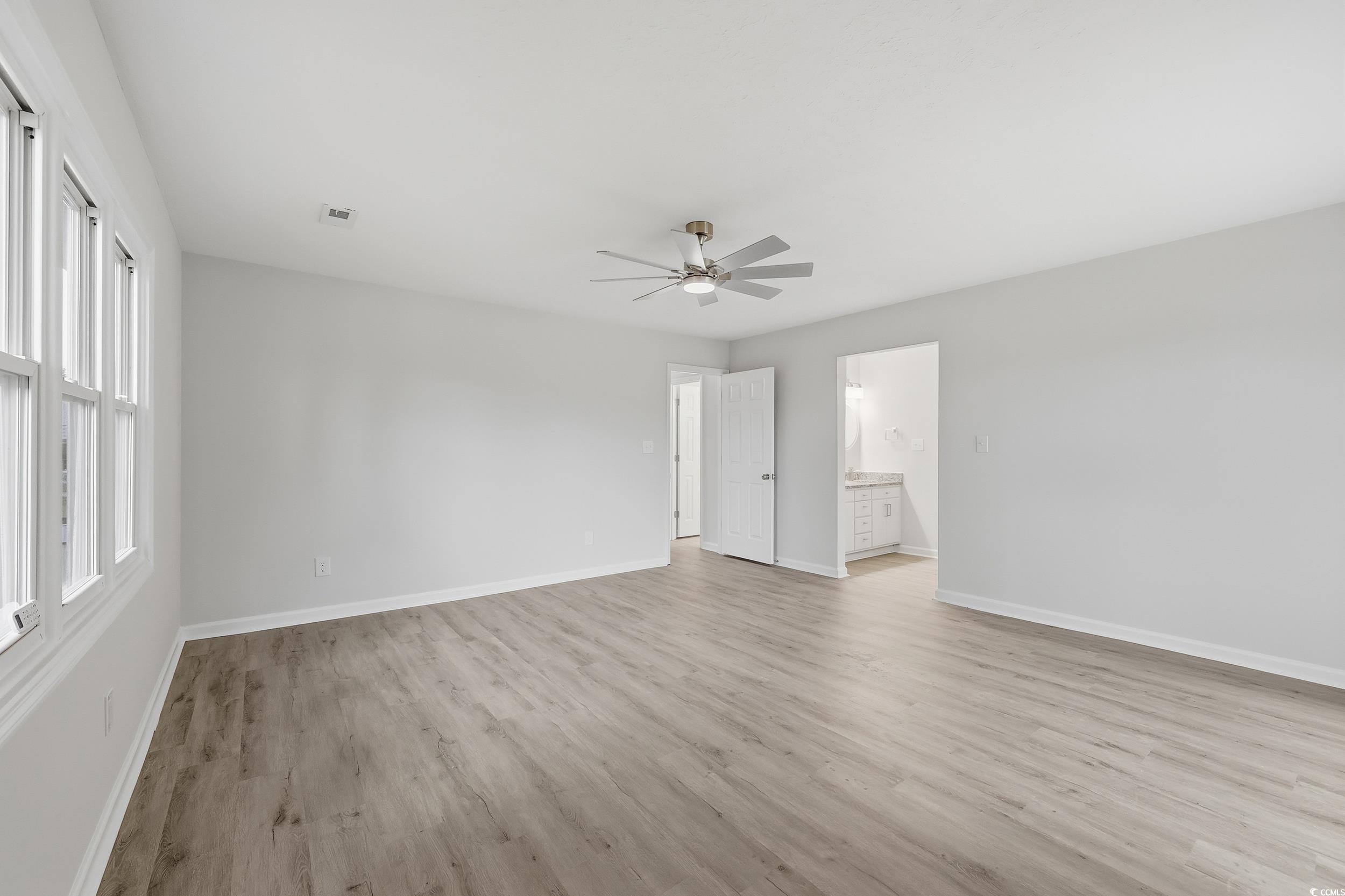 Unfurnished bedroom featuring light wood-style floors, a ceiling fan, and ensuite bathroom