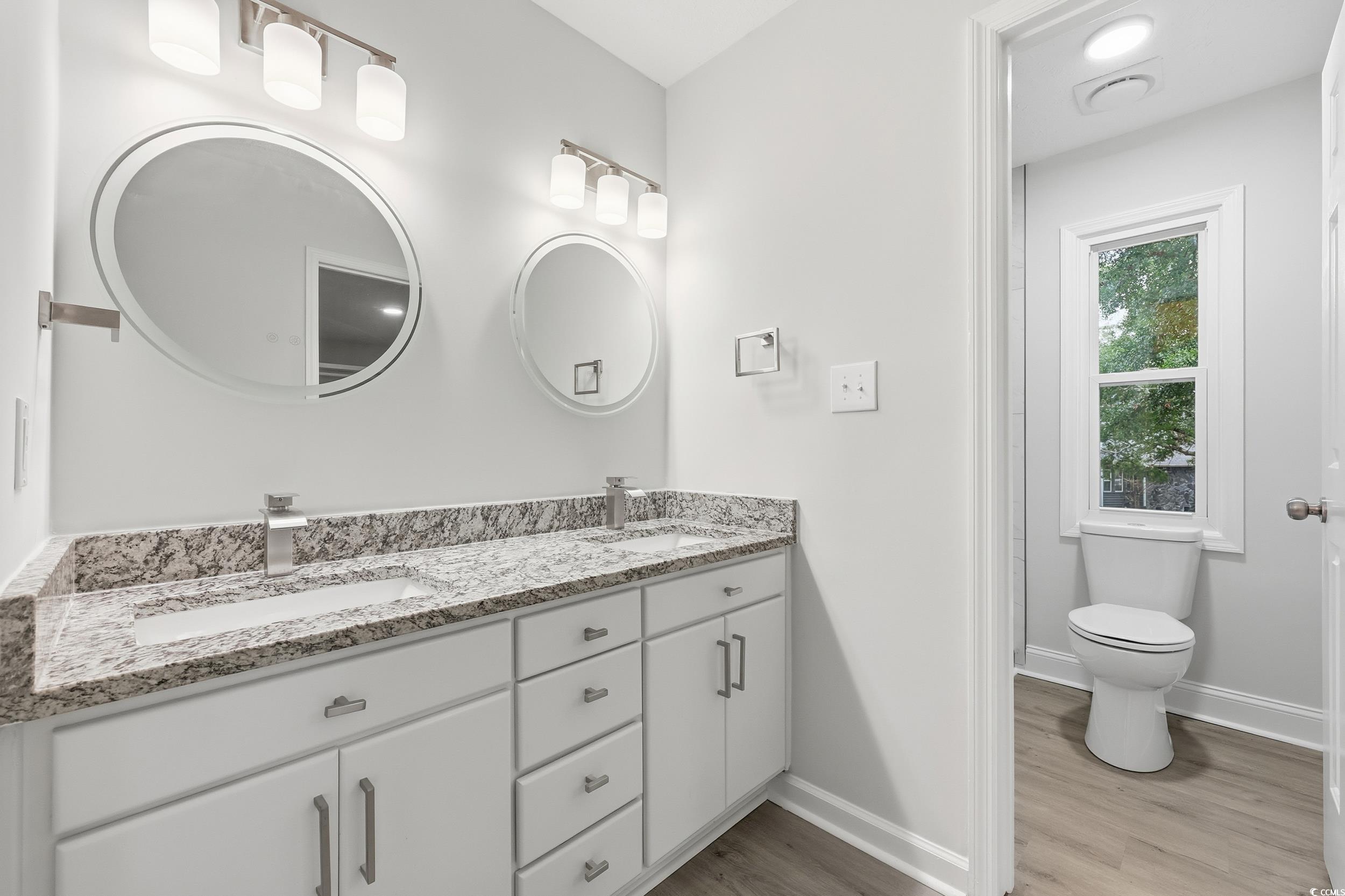 Bathroom with double vanity and light wood-style floors