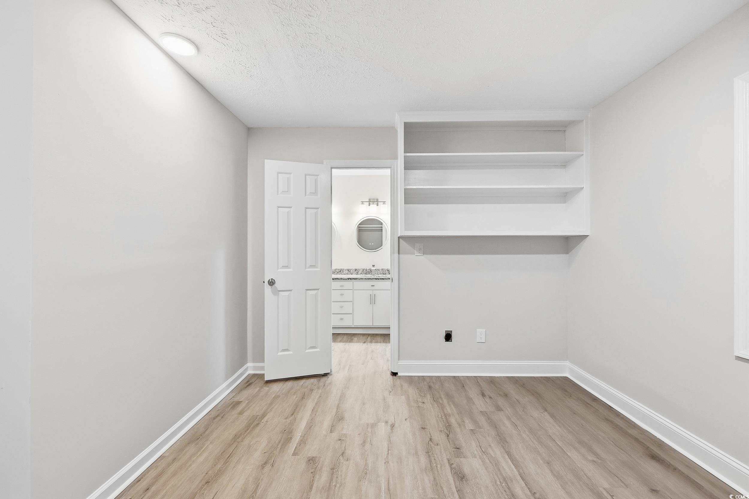 Washroom with light wood-type flooring and a textured ceiling