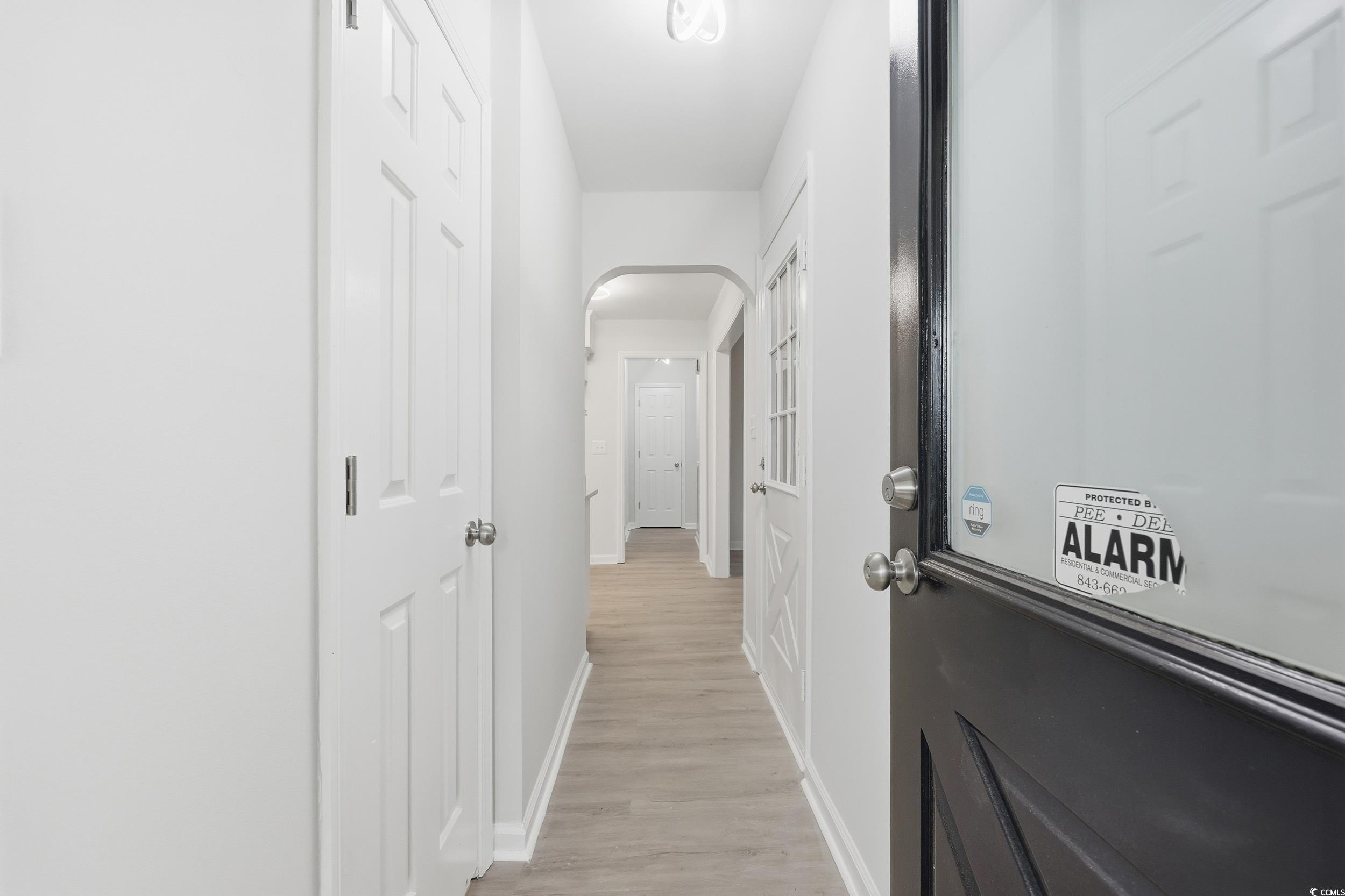 Hall featuring arched walkways and light wood finished floors