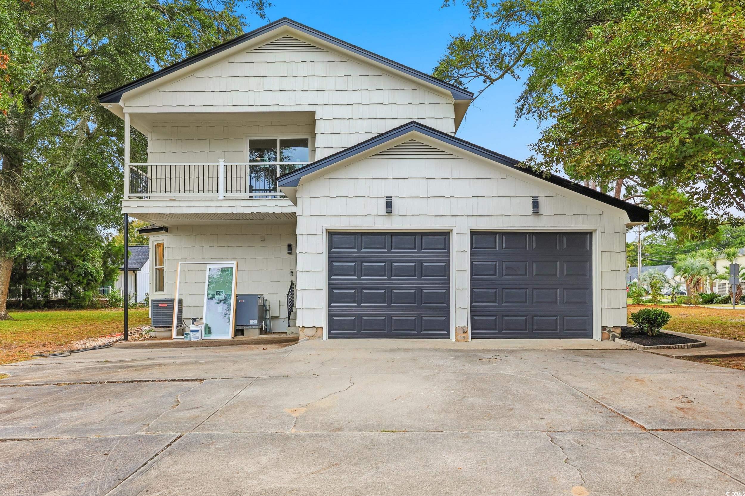 View of front of property with a balcony, concrete driveway, and a garage