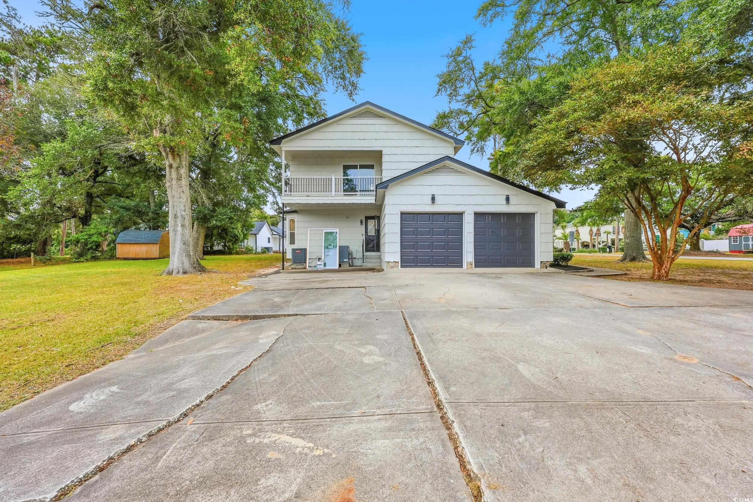 Traditional-style home featuring a front lawn, concrete driveway, a balcony, and a garage