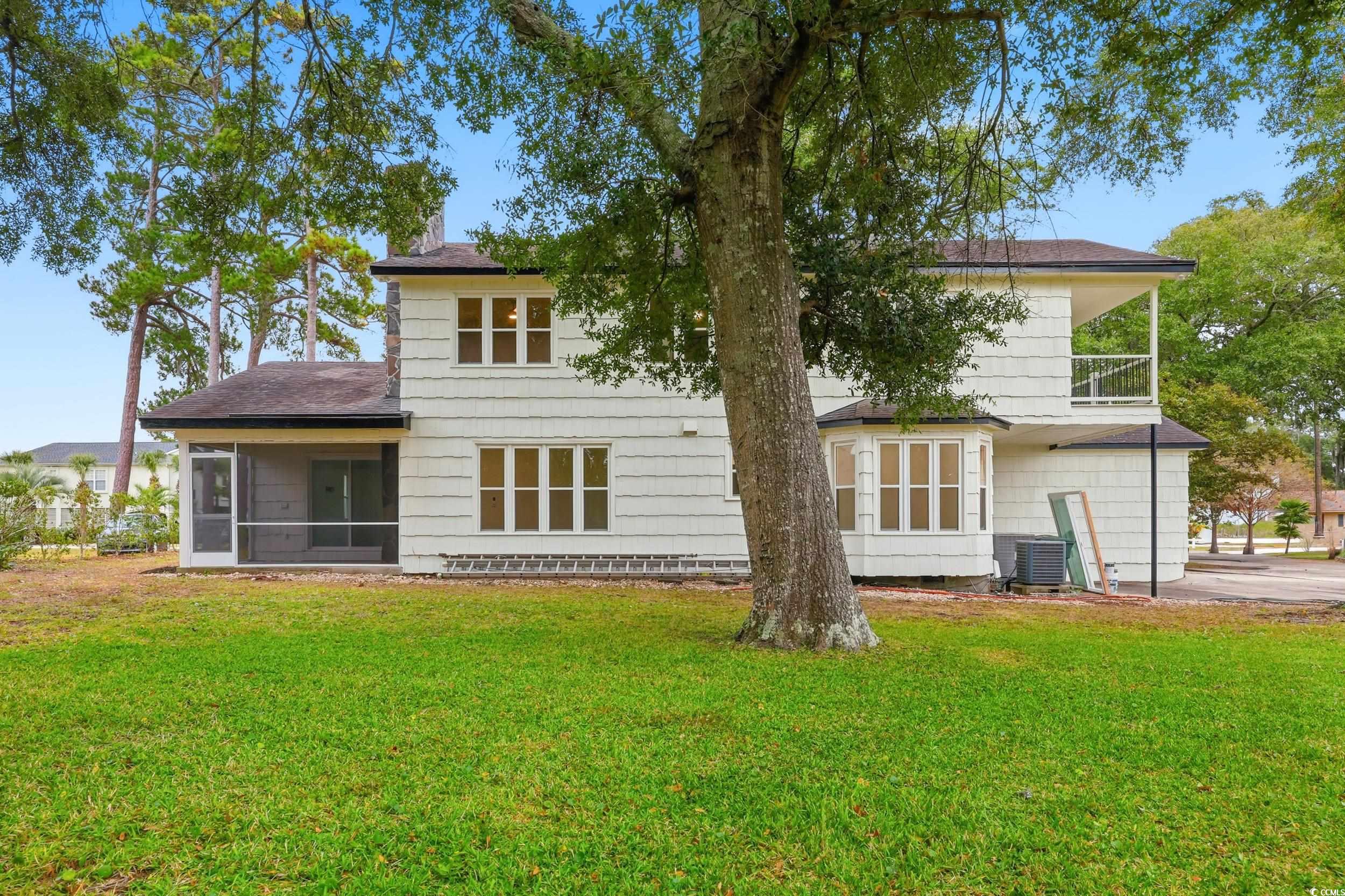 Back of property with a yard, a sunroom, and a shingled roof
