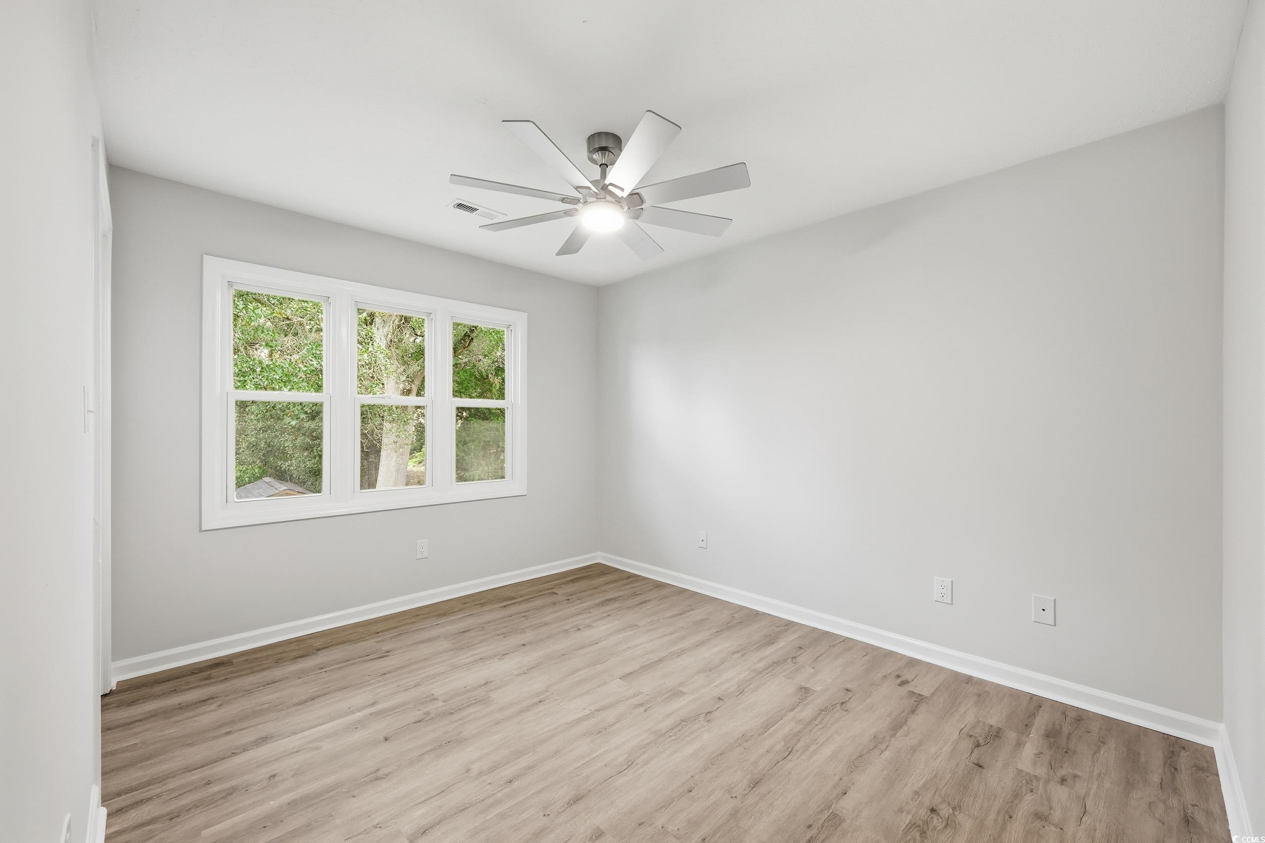 Spare room with light wood finished floors and a ceiling fan