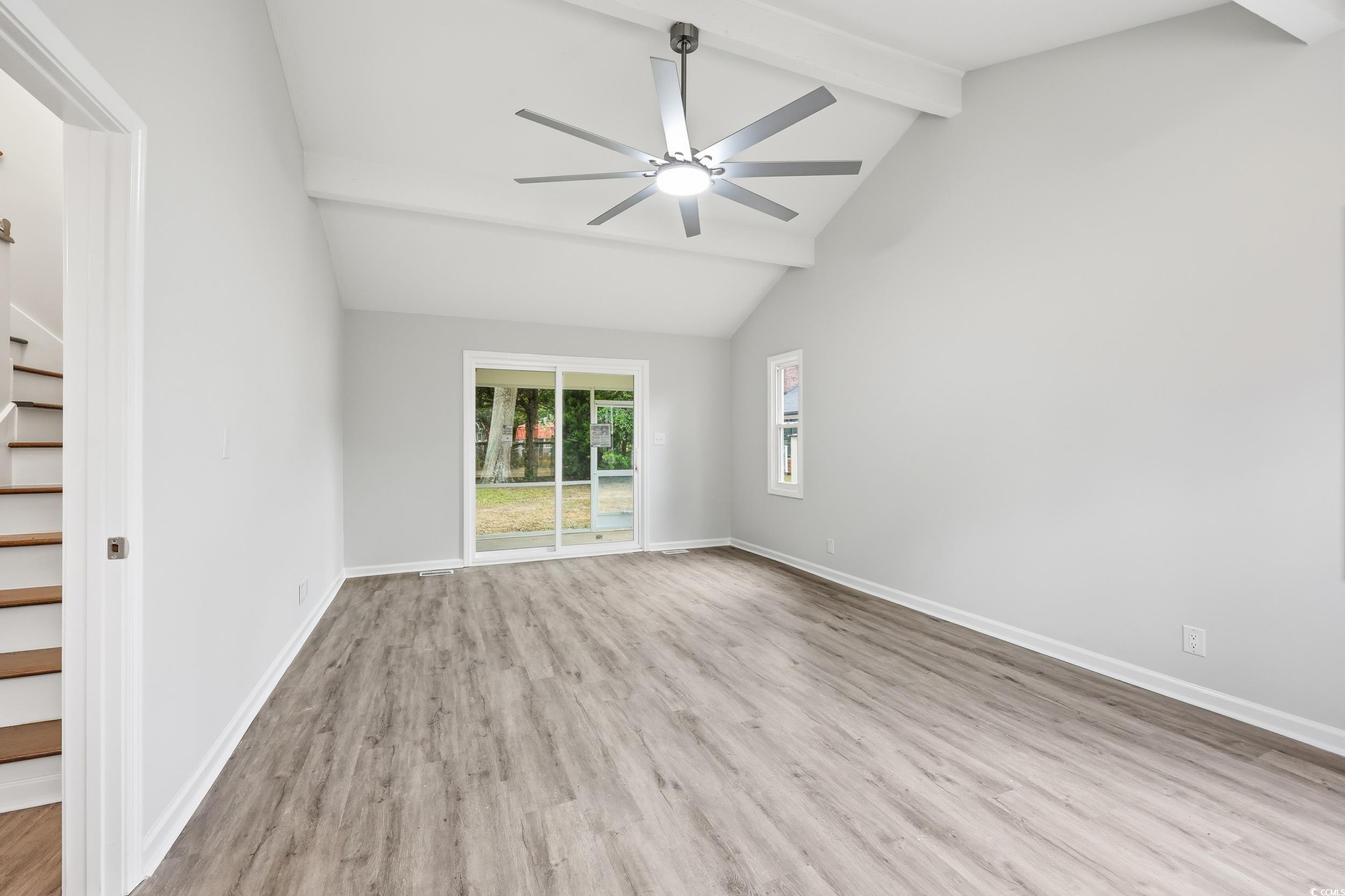 Unfurnished room with beam ceiling, light wood-type flooring, a ceiling fan, high vaulted ceiling, and stairs