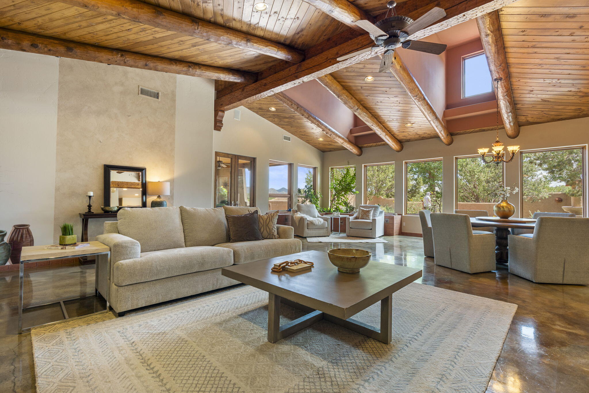 Artistic Mountain Home set on 10.14 private acres in San Pedro Creek, this distinctive 4 bedroom, 4 bath home is a true work of art- blending traditional Santa Fe design with creative, custom craftsmanship throughout. Built to inspire, the residence features expansive open-concept living with polished concrete floors, a dual-sided fireplace connecting the living and library areas, and large windows that frame panoramic views of ridges and endless skies. The kitchen is warm and welcoming, with artisanal cabinetry, handcrafted tile, and a layout that encourages gathering and creativity. The home features two separate bathrooms and walk-in closets within the primary bedroom making this space truly one of a kind! As you walk through, you'll be surrounded by beauty