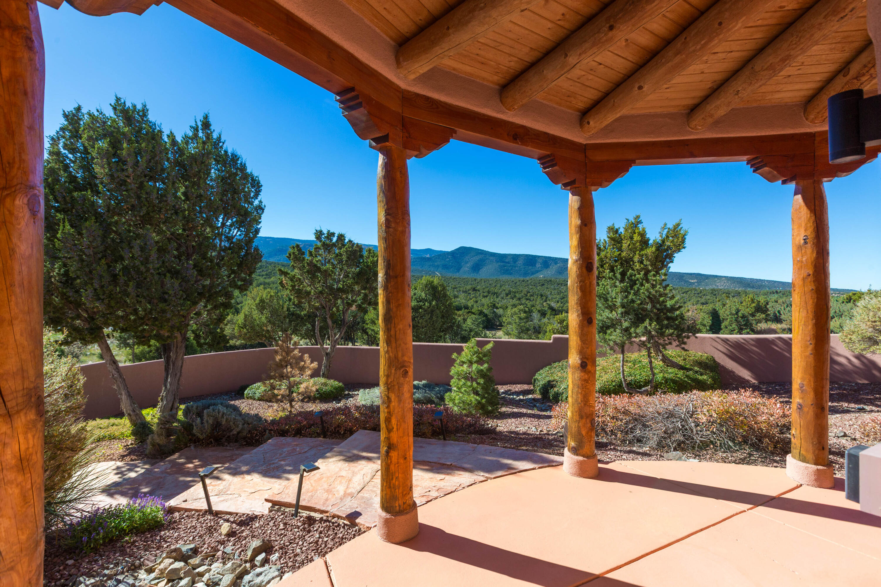 Experience the essence of high-end Northern New Mexico architecture, perfectly set against the backdrop of the breathtaking Cibola National Forest. This unique property boasts unobstructed views that discerning buyers will truly appreciate. From the moment you step into the enchanting foyer and journey through the home, you'll be captivated by the luxurious finishes. Marvel at the multiple kiva fireplaces, the soaring viga ceilings with clear vistas of the Sandias, and the clay plaster walls enriched by beautiful handcrafted hardwood and gleaming Mexican Saltillo tile flooring. Warm earth tones throughout create an inviting atmosphere, perfectly complemented by the radiant heat that you'll seldom need, thanks to the home's highly efficient RASTRA construction. Unwind in the sumptuous