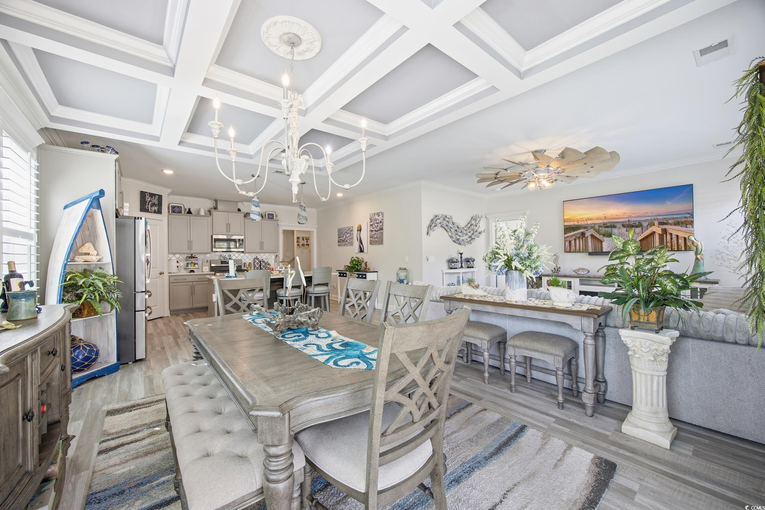 Dining area featuring crown molding, light wood-style floors, beamed ceiling, coffered ceiling, and a chandelier