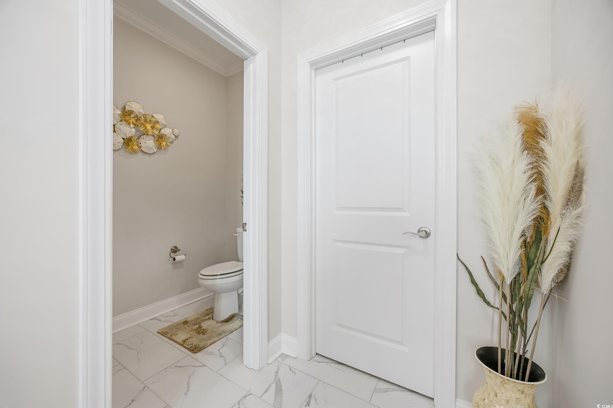 Bathroom featuring light marble finish floors and crown molding