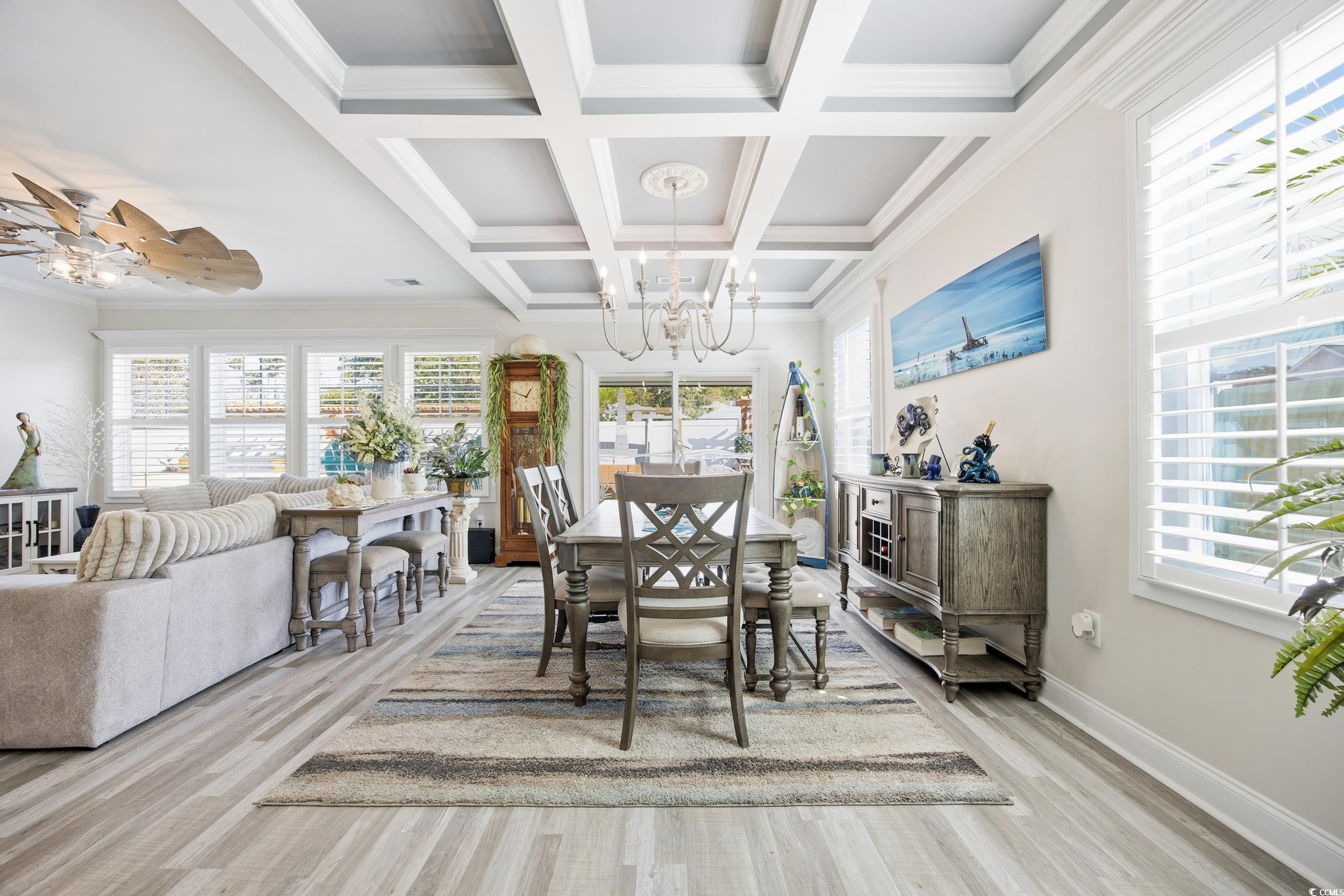 Dining space with healthy amount of natural light, light wood-type flooring, beam ceiling, crown molding, and coffered ceiling