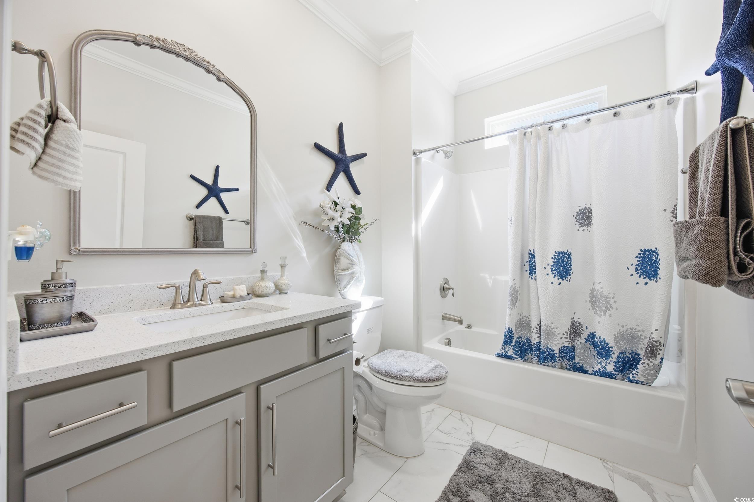 Bathroom with shower / bath combo, ornamental molding, vanity, and light marble finish flooring