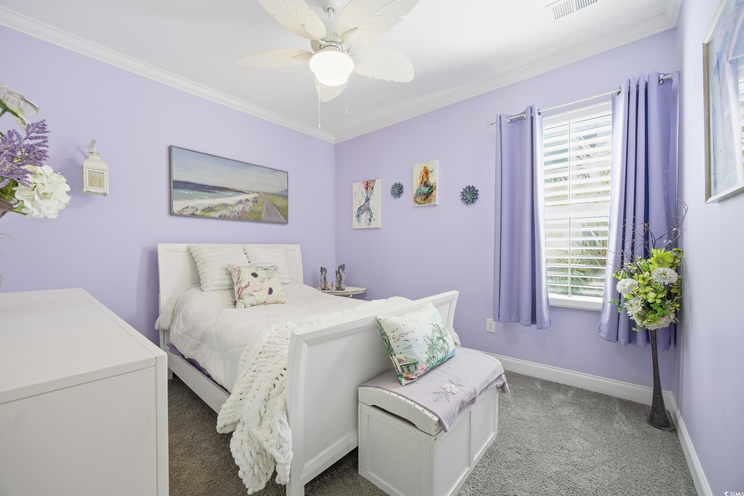 Carpeted bedroom featuring ornamental molding and a ceiling fan