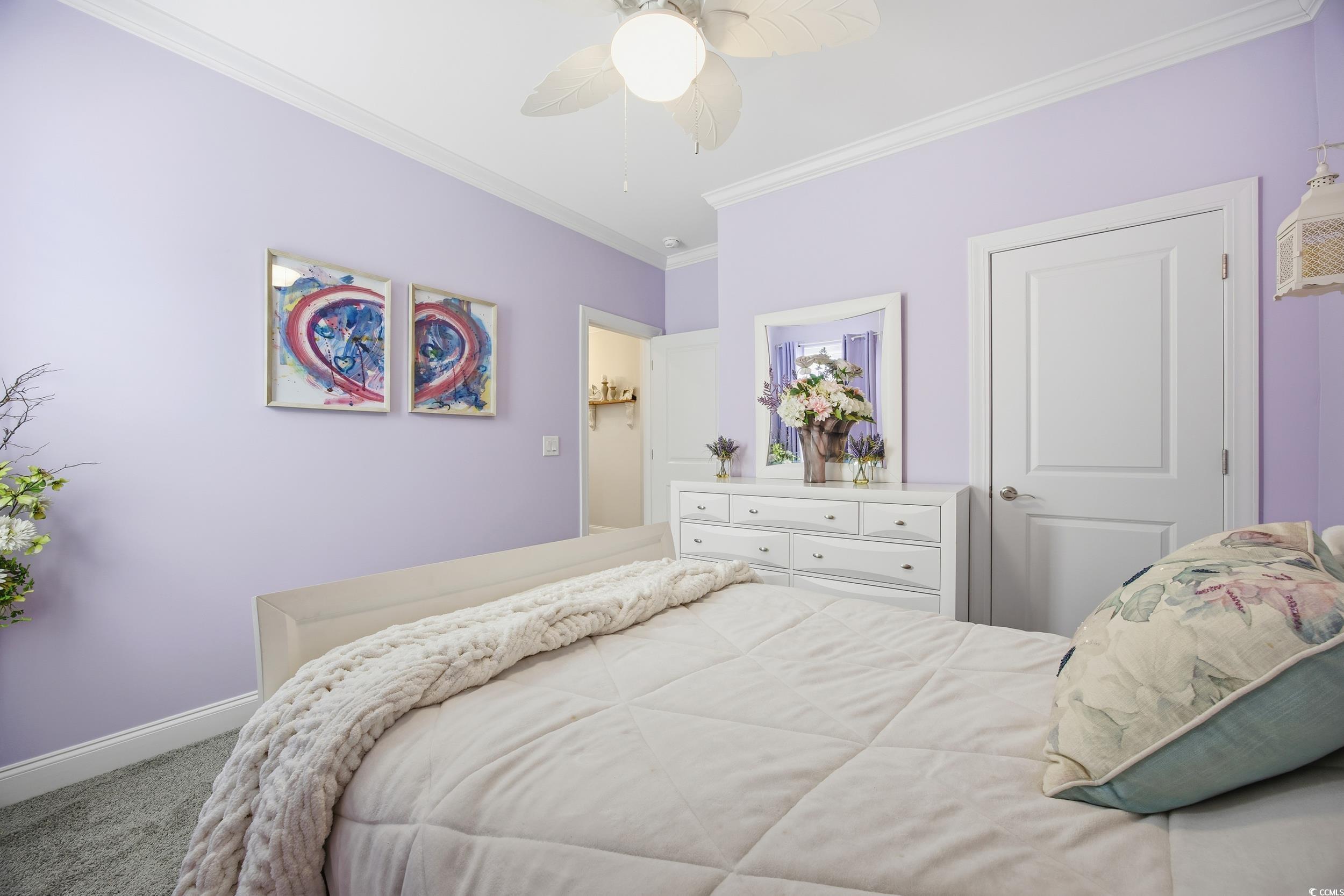 Carpeted bedroom featuring crown molding and a ceiling fan