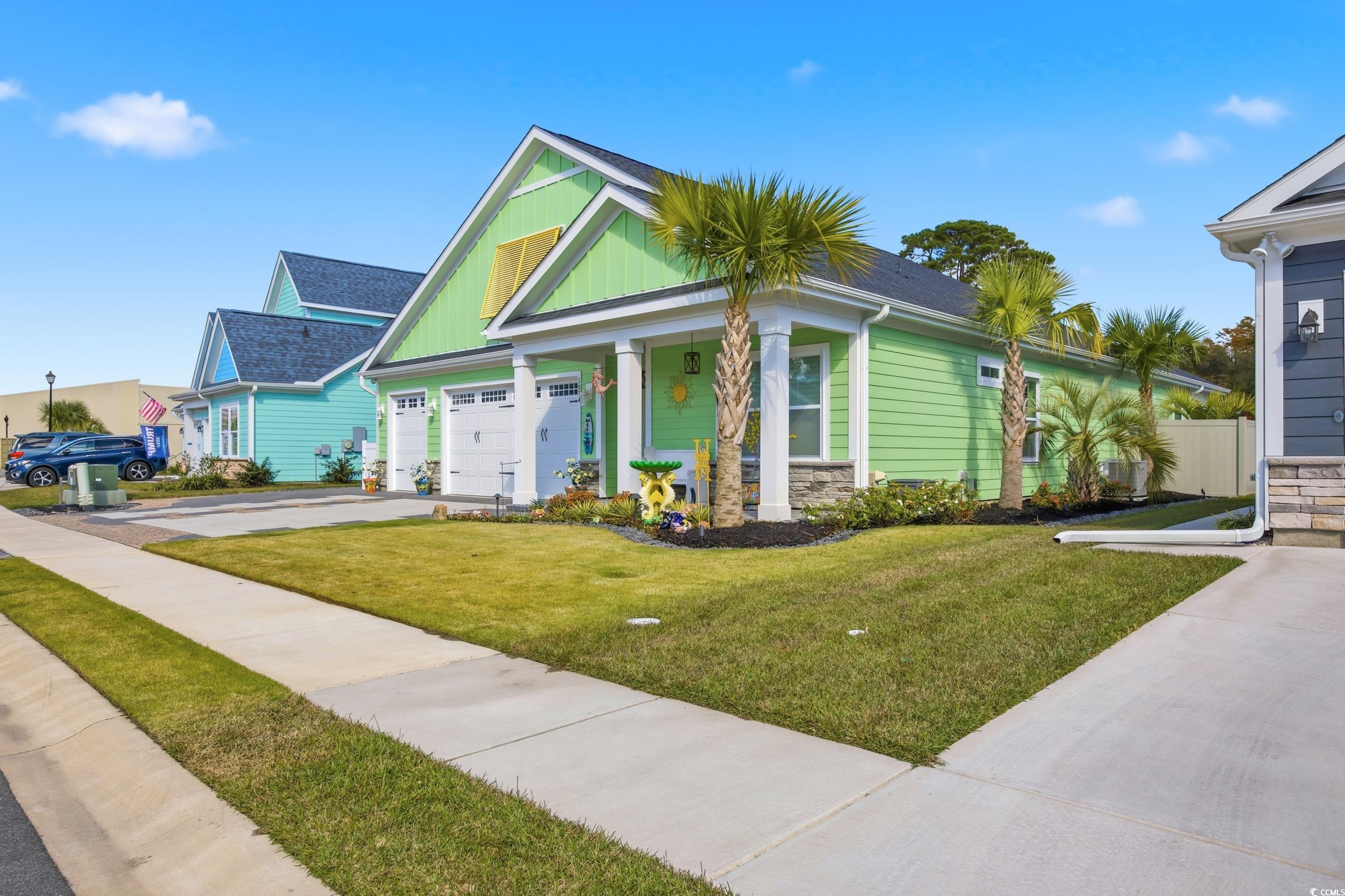 View of front of house featuring a front lawn, covered porch, stone siding, and driveway