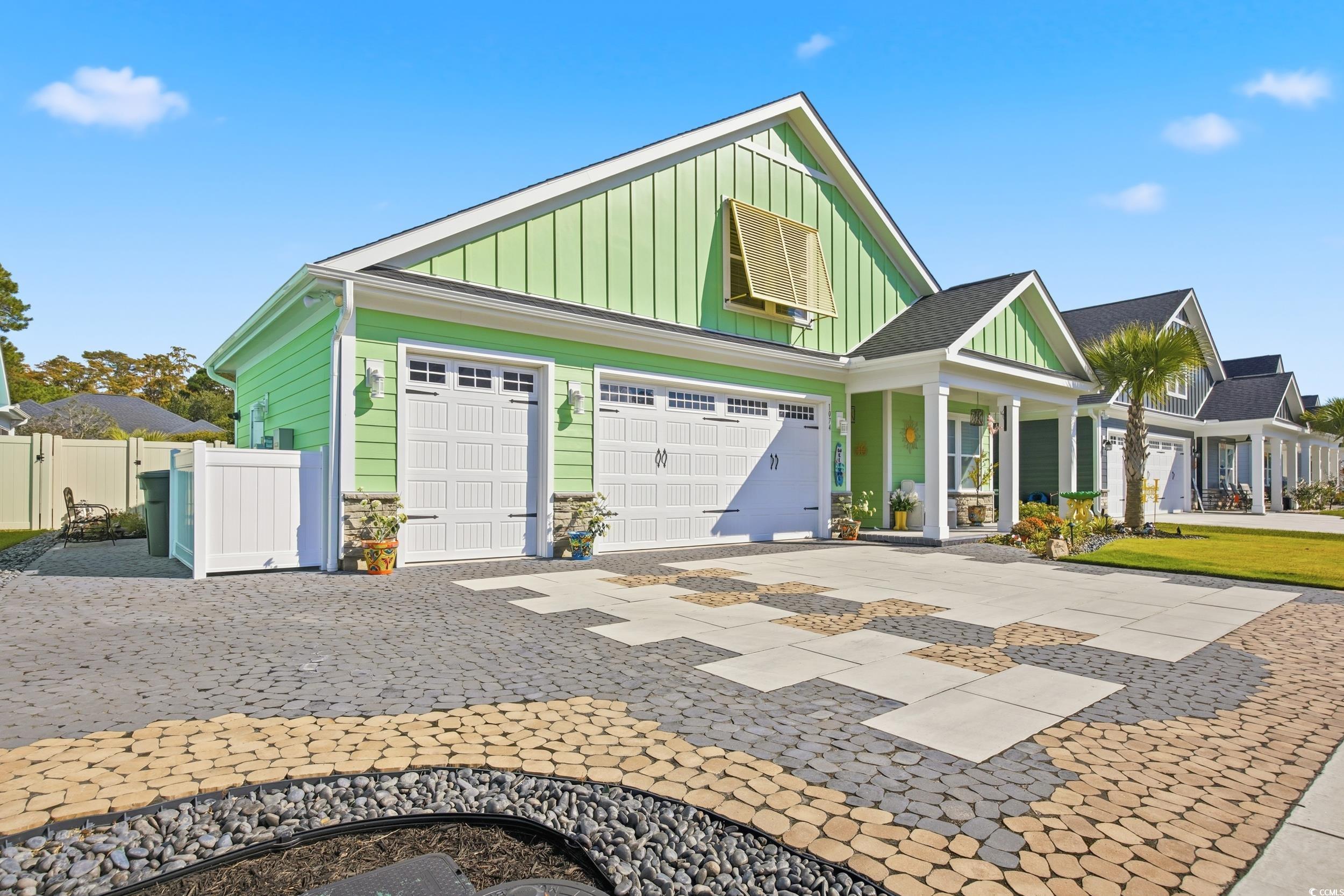 View of front of property featuring board and batten siding, decorative driveway, a garage, and covered porch