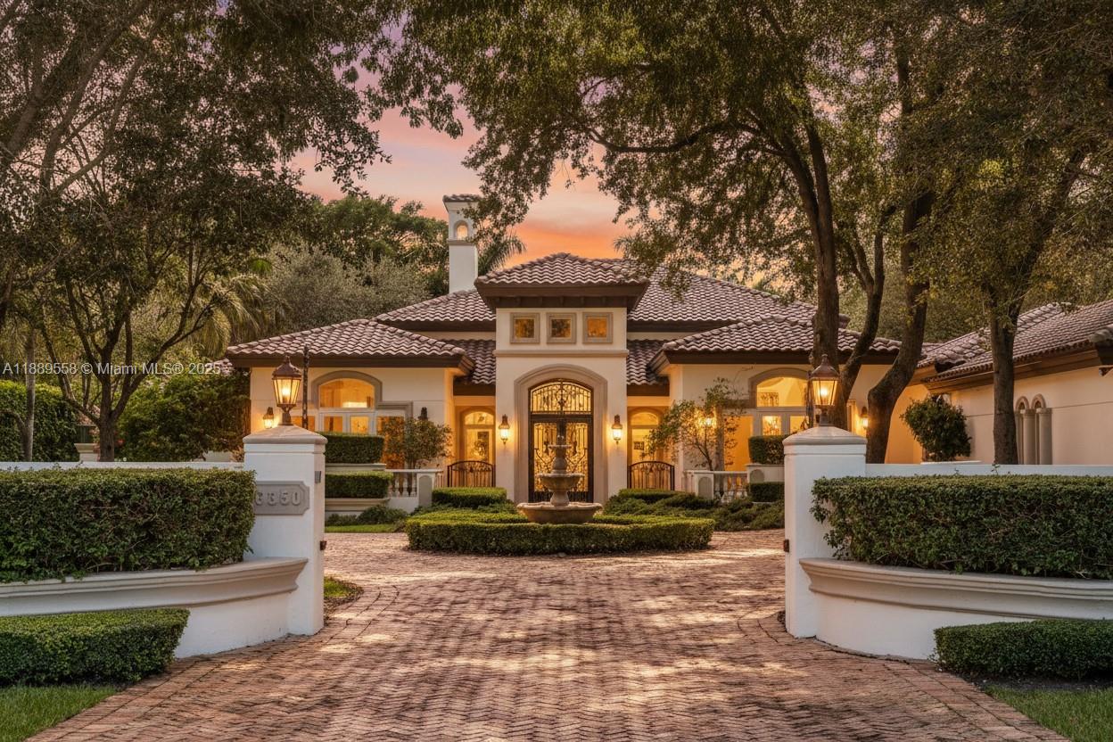 Elegant Mediterranean estate nestled in the heart of Pinecrest on a magnificent 47,916 sq ft lot, offering 5,992 sq ft of refined living space. This 6-bedroom, 5.5-bath residence showcases soaring vaulted ceilings, a wood-burning fireplace, and plantation shutters throughout. The gourmet kitchen, wet bar, and expansive living areas create an exceptional setting for entertaining. The primary suite boasts his-and-hers vanities and custom built-in closets. Outdoors, enjoy a resort-style ambiance with a stunning pool, gazebo, and lush landscaping. A circular driveway with fountain, 3-car carport, brand-new roof, full house generator, and a completely repainted interior elevate this home’s timeless elegance and modern comfort.