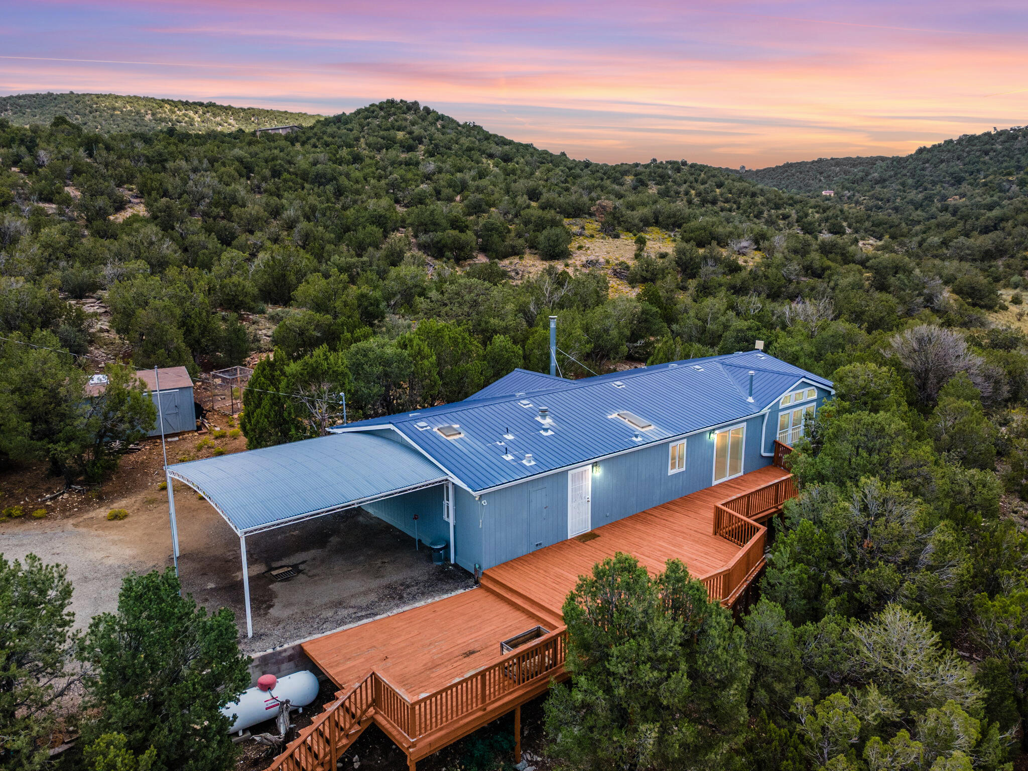 Imagine waking up to the forest surrounding you, viewing the sunrise over the rolling hills of Sandia Knolls, and enjoying your morning coffee on the expansive deck. Start your day venturing into your 13 acres of land, and when you're ready to retreat inside, enjoy an updated and open floorplan with refrigerated air, newer flooring, and two fireplaces to cozy up to. You have your own private well, and the newer water filtration system is superb! Conveniently located just minutes from Albuquerque, this retreat is a perfect balance of rural living with the benefits of city life a short drive away.