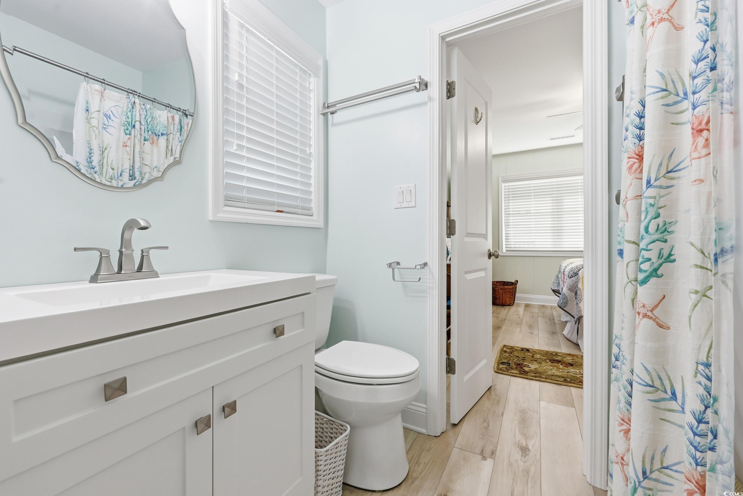 Full bathroom with vanity, light wood-style floors, and a shower with curtain