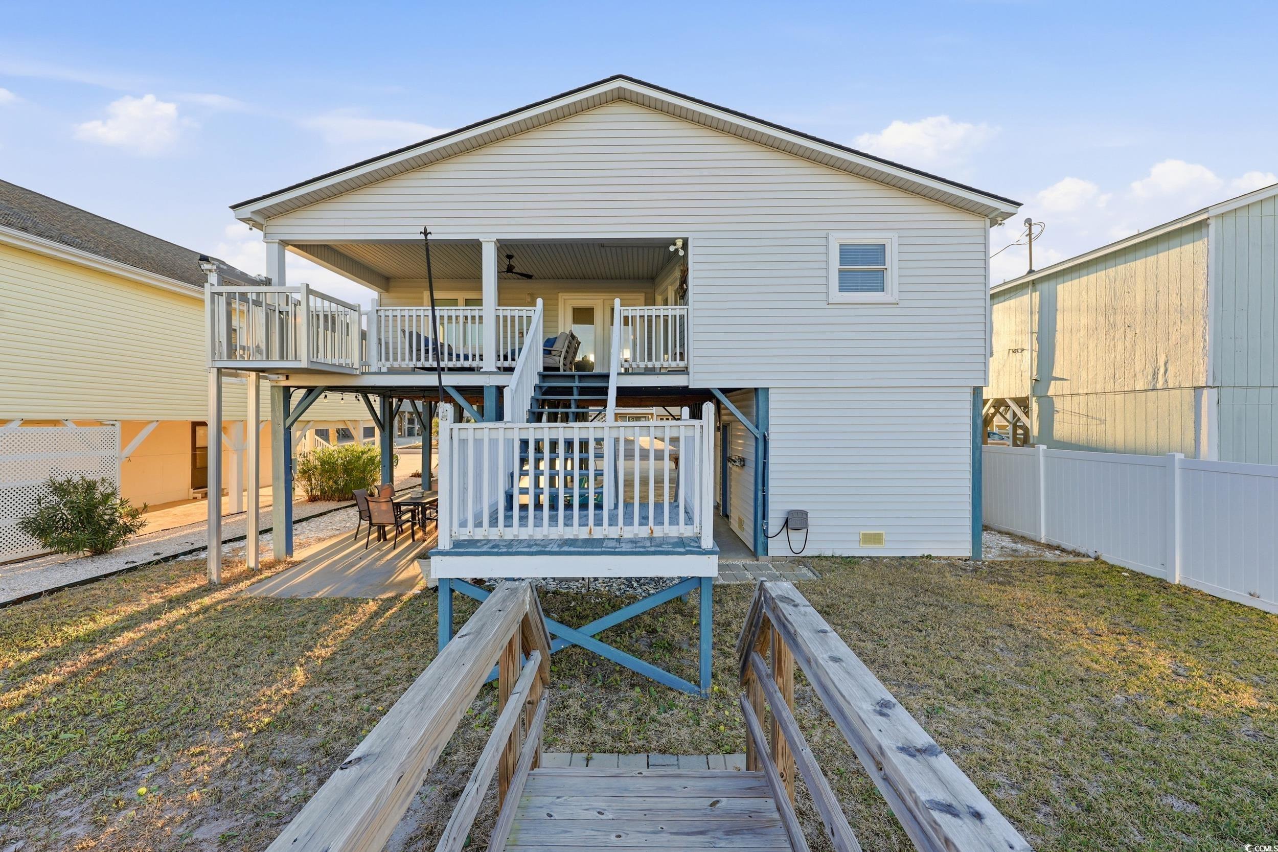 Back of house with stairway, a wooden deck, and a patio