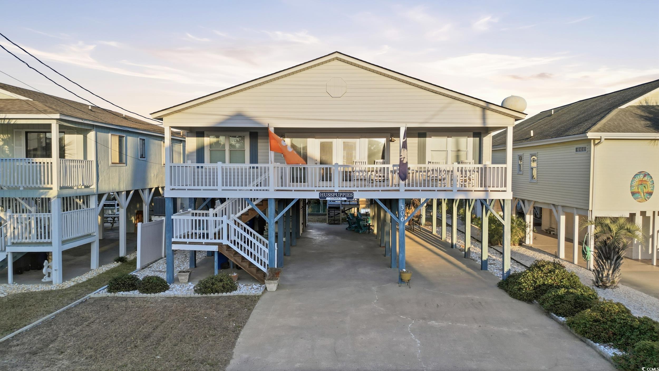 Back of property featuring a carport, concrete driveway, stairs, and a wooden deck