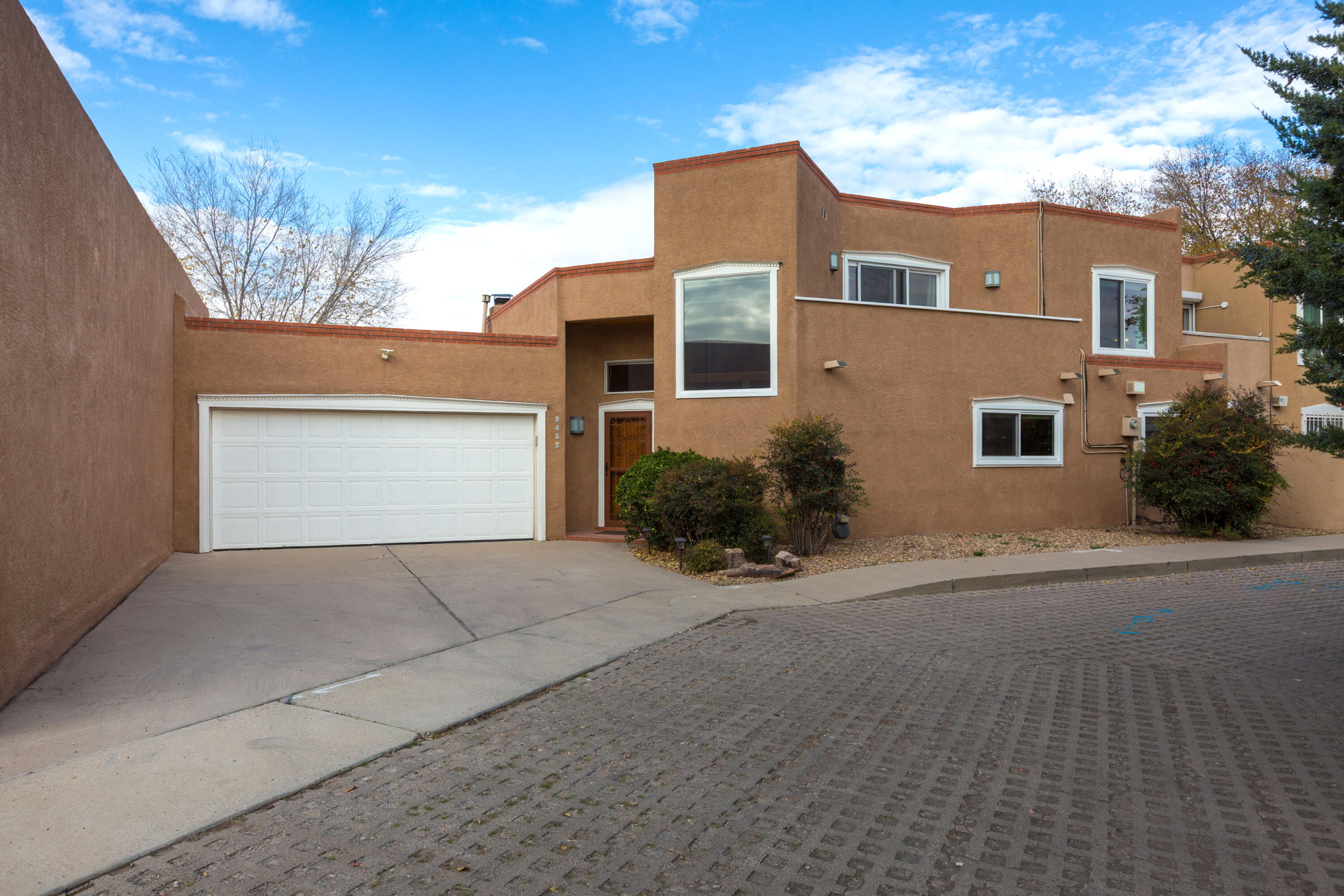 Stylish updated townhome off Rio Grande on a quiet cul-de-sac providing North Valley ambiance and convenience to downtown, hospitals and shopping. High ceilings and new windows throughout provide light and privacy. Greatroom has custom kiva fireplace, dining area, and attached heated  sun room with custom shades for use year round. Sunroom opens onto a charming back patio area.  Kitchen has newer appliances, granite counters, large pantry. 2 bedrooms with California closets and upscale bath complete the 1st floor. Upstairs is a private, large primary suite with balcony to watch the sunrise. The primary bath has updated granite counters, large shower, and walk in California Closet. Ductless mini-split provides extra cooling in Primary.  Don't miss this great find!