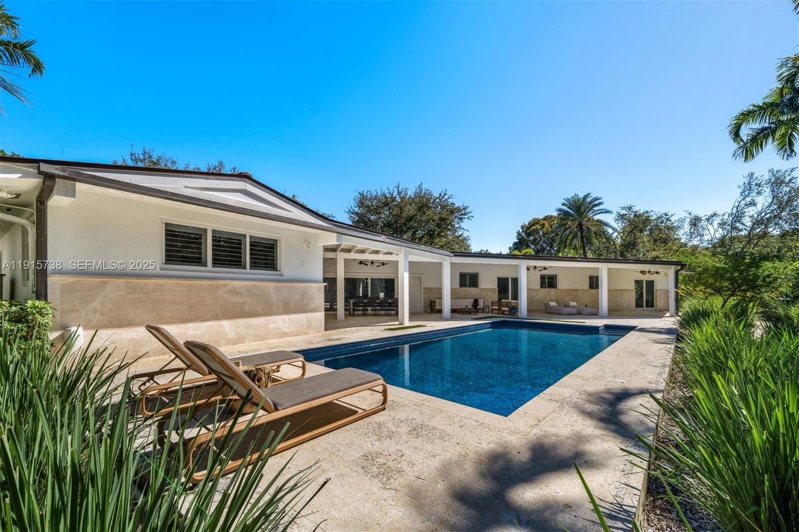 This fully renovated contemporary estate in the heart of Pinecrest offers 3,191 SF of refined living on a 26,963 SF lot. Flooded with natural light, the home features impact windows, plantation shutters, and large-format grey porcelain tile floors. The open kitchen showcases Italkraft custom cabinetry, striking grey quartzite countertops, and premium appliances. A serene primary suite includes a spacious walk-in closet and a spa bath. Outdoor living shines with a sprawling covered terrace and a breathtaking naturalistic grotto waterfall and emerald pool, complemented by a saltwater heated pool, lush landscaping designed by Raymond Jungles, solar panels, and an AC-equipped 2-car garage.