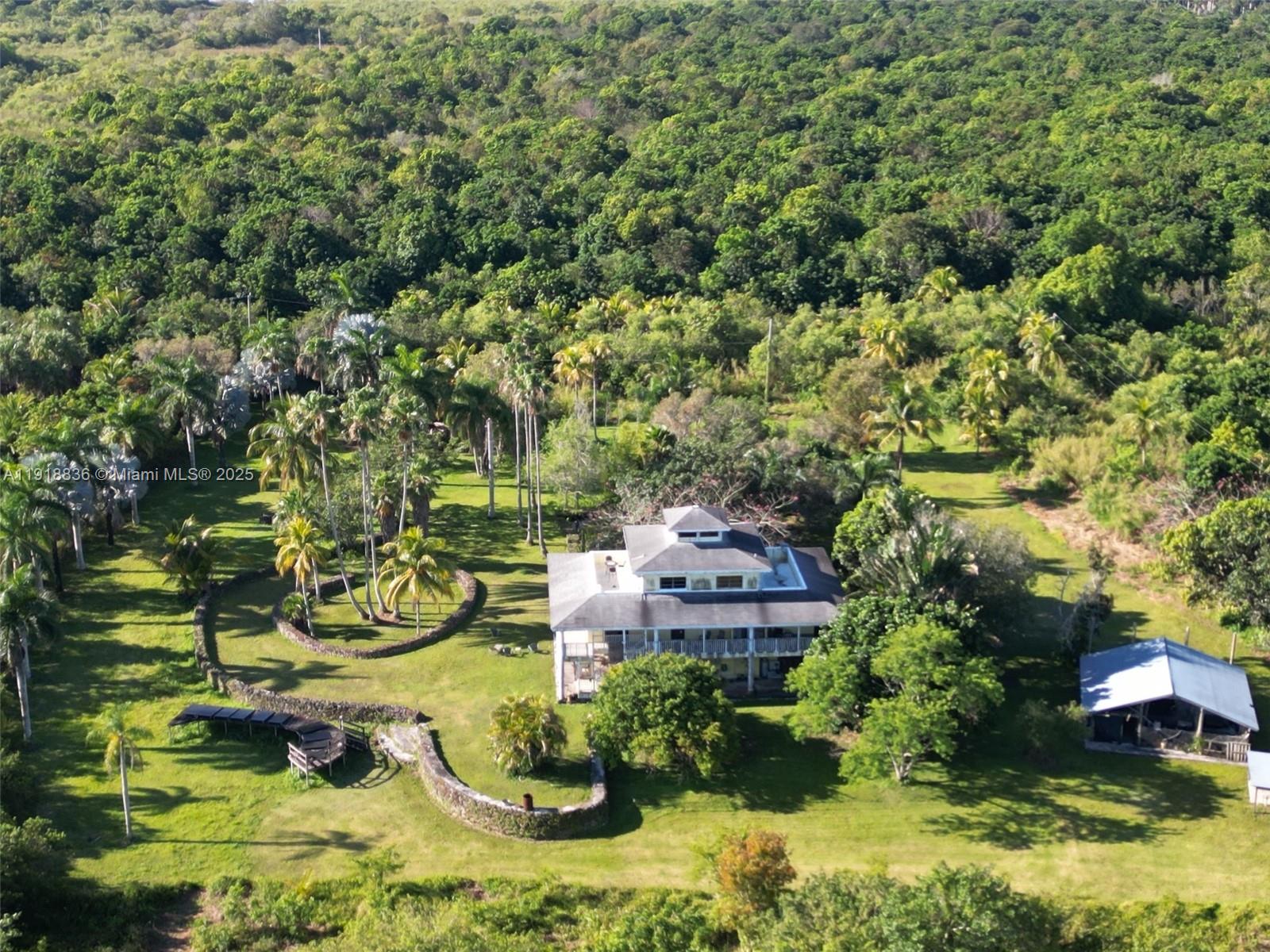 Everglades Paradise is a hilltop 3-story masterpiece of architecture on almost 5 acres that sits at the edge of the Everglades, where neighbors are down the road, not next door.  Less than an hour from downtown Miami and just 15 minutes to the gateway to the Florida Keys and the city centers of Homestead and Florida City.  This spacious home, while comfortably livable, has a rustic, unpolished character that invites your personal updating inside and out.  Enjoy your own star fruit year round and mangos & lychees every spring.  Starlink, Comcast Fiber and Verizon 5G keep you connected.The first floor, with marble floors, is currently used as a private apartment/office with a large living area, a bedroom (used for exercise & storage) and bathroom. Its glass sliding doors open into a screened patio with more marble floors that afford dramatic views of the landscaped surroundings. The second story is open to the third floor and has 3 bedrooms, 2 bathrooms and a great room combined with an open kitchen. All of the second-floor living spaces have glass sliding doors that open to a sweeping wrap-around veranda that extends the inside area to the natural beauty outdoors. The third floor loft opens to east & west terraces with expansive views of the Everglades and surrounding farmland, stretching to the horizon.  2nd & 3rd floors all Mexican tile.