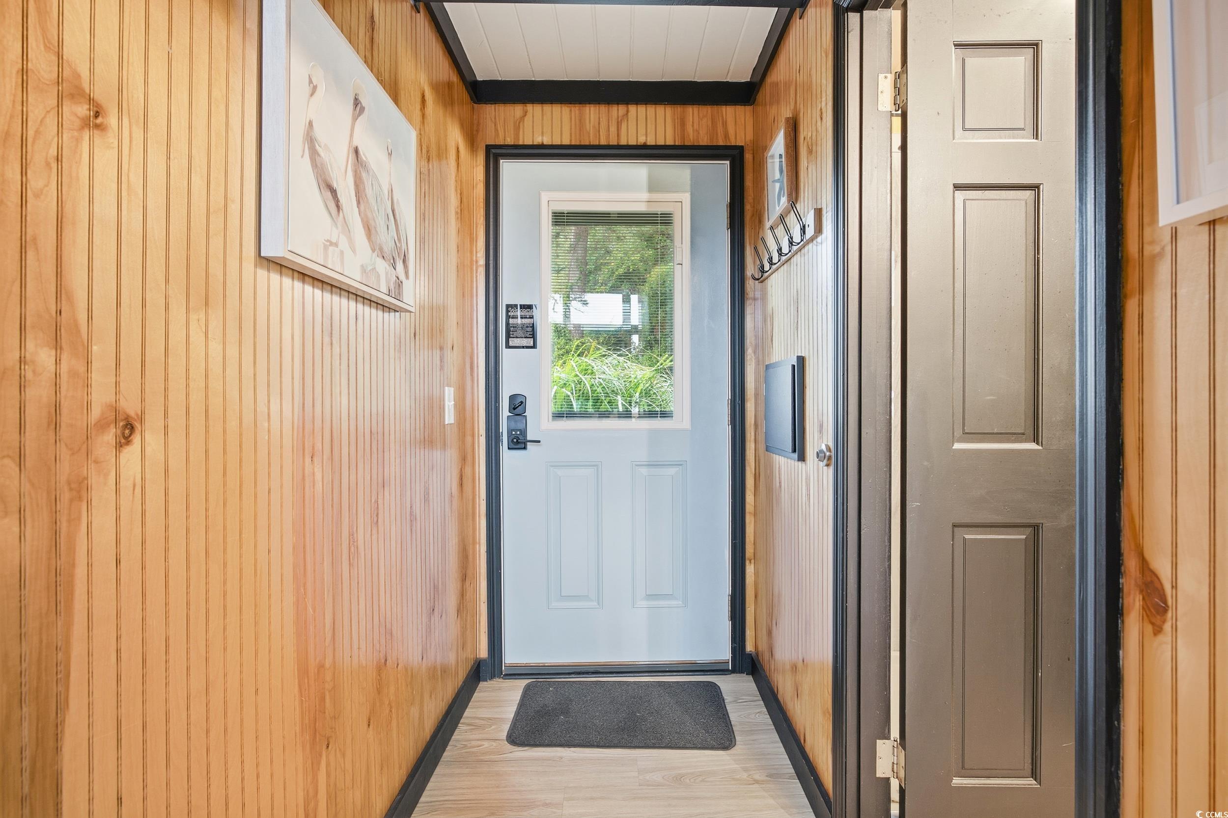 Doorway to outside featuring wood walls, elevator, and wood finished floors