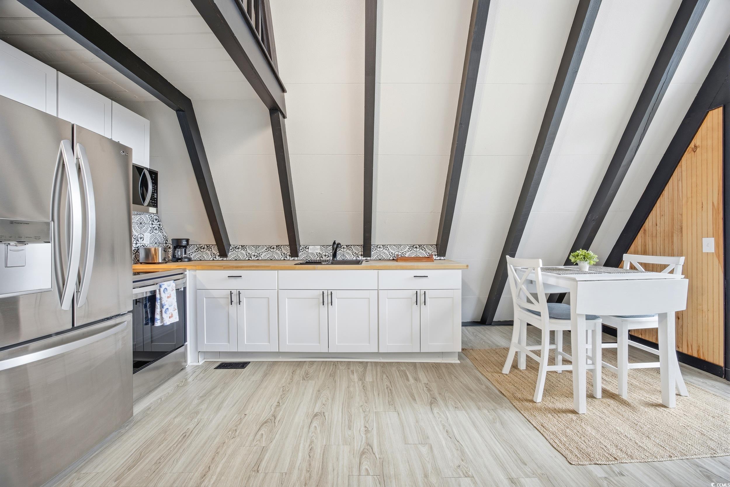 Kitchen featuring stainless steel appliances, white cabinets, wood counters, and light wood finished floors