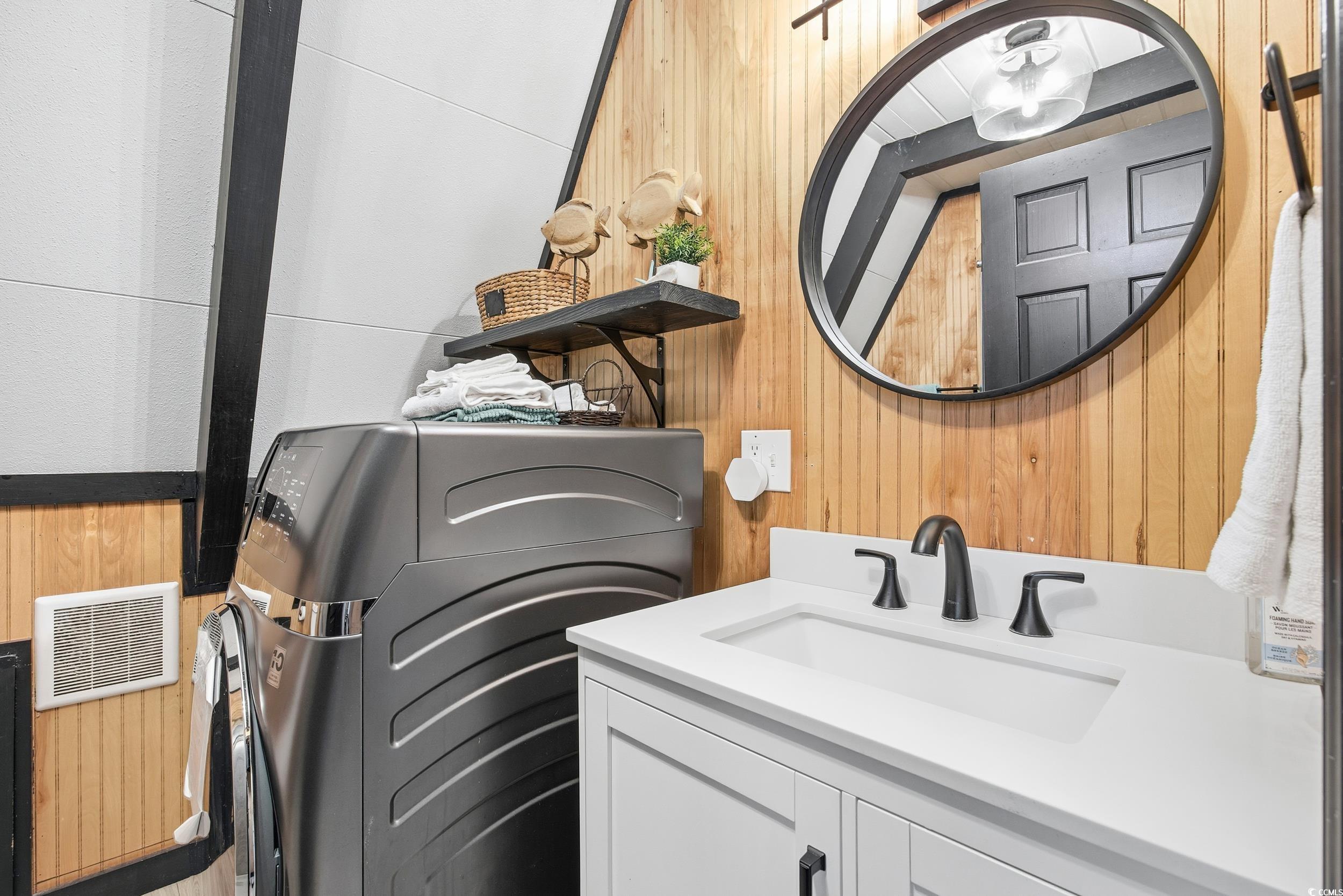 Laundry room featuring washer / clothes dryer and wood walls