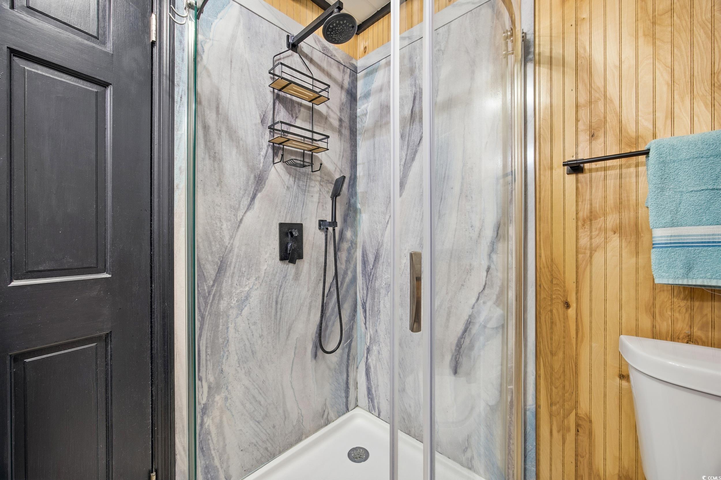 Bathroom featuring a marble finish shower and toilet