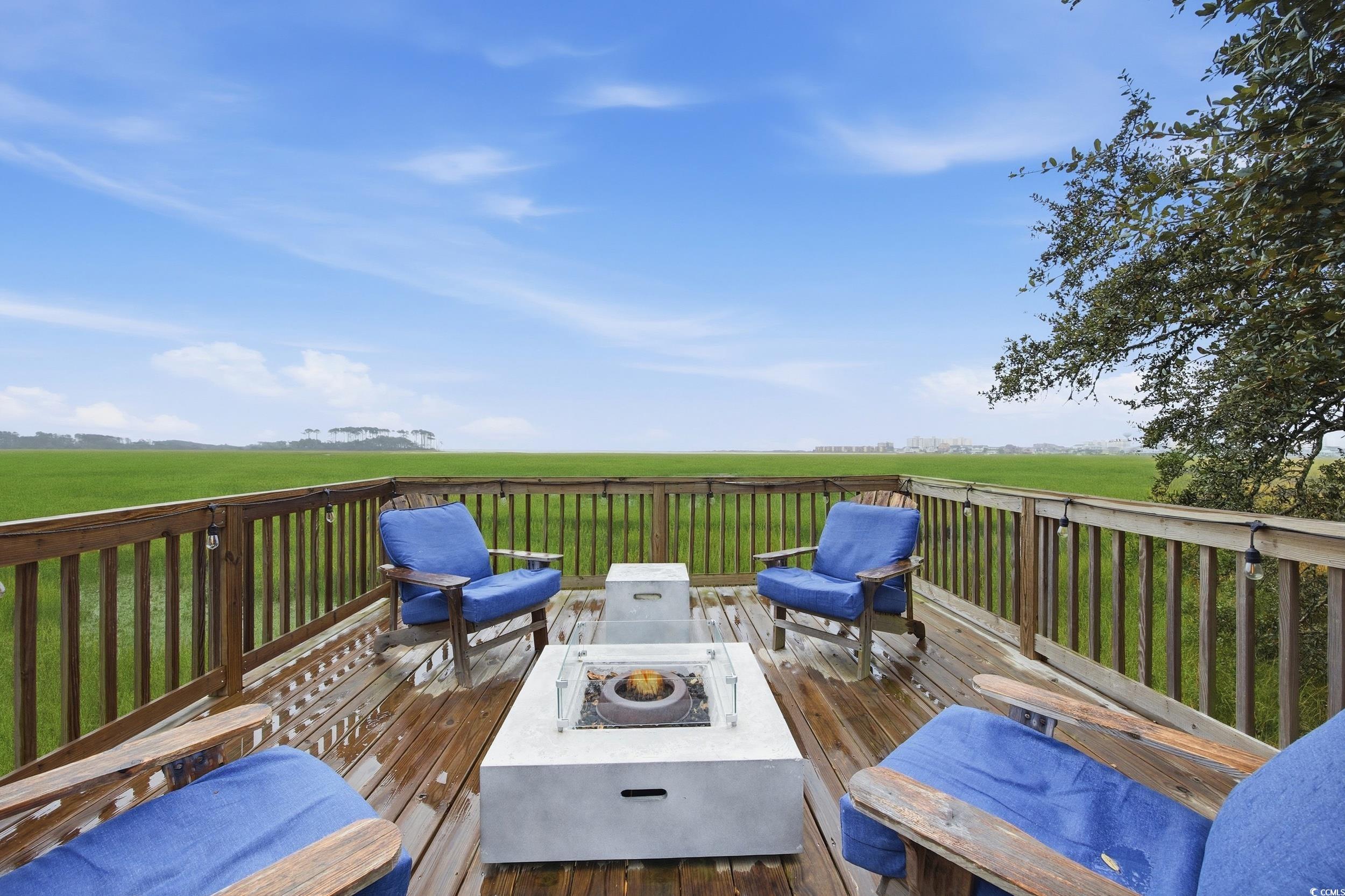 Deck with an outdoor fire pit, a lawn, and a view of countryside