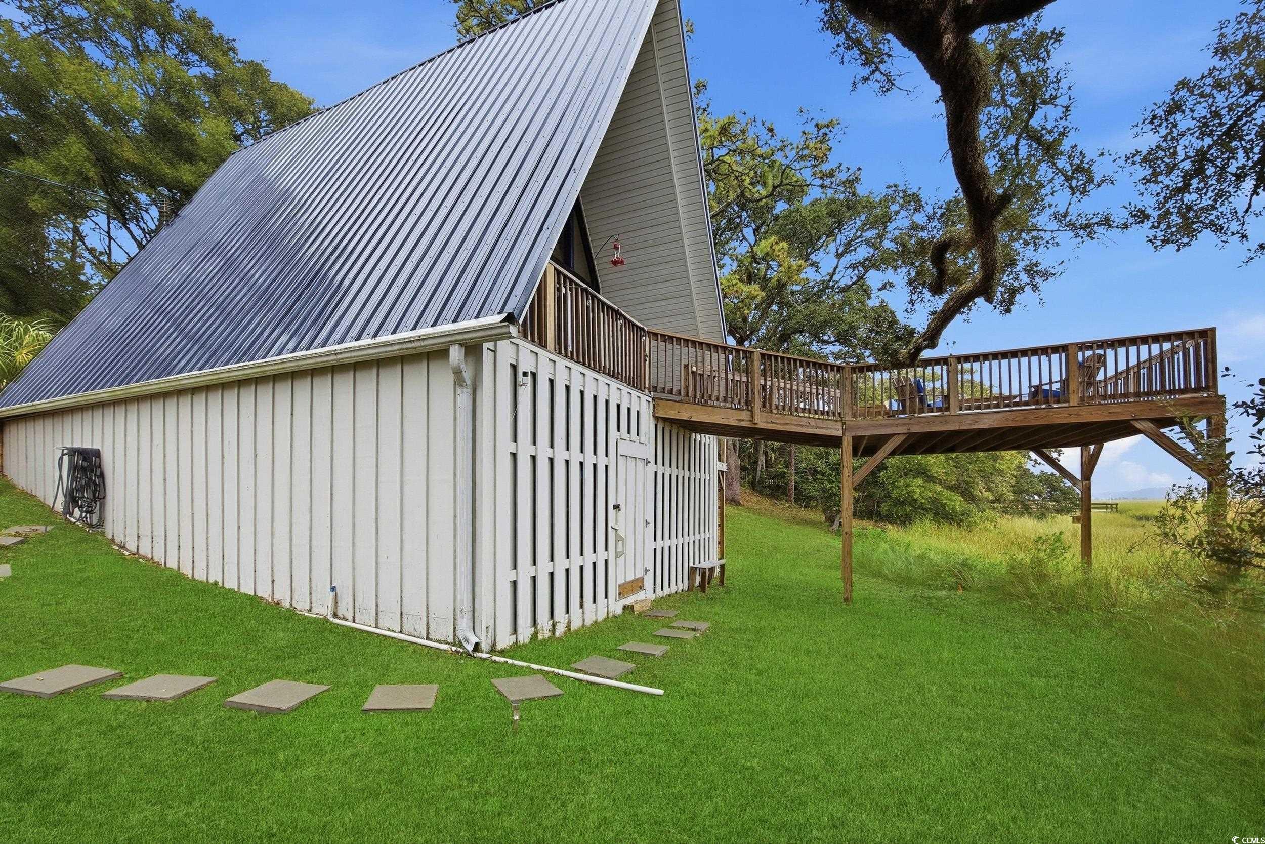 View of property exterior featuring a deck, a yard, and a metal roof