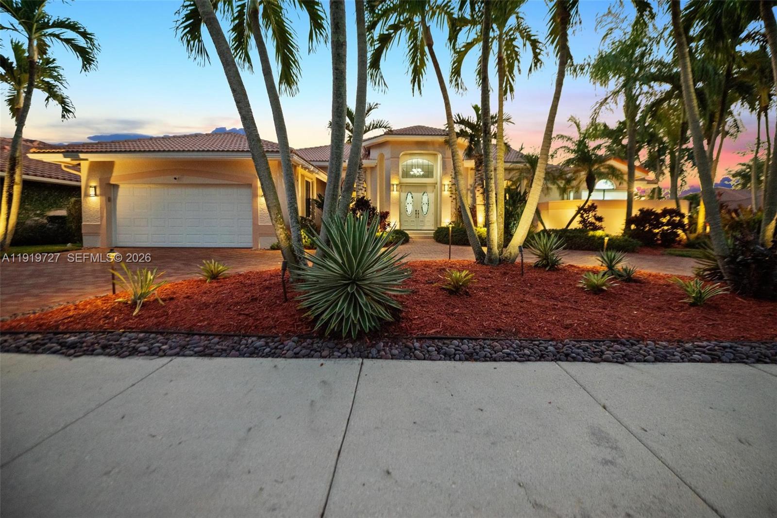 This elegant residence is set on a private oversized corner lot within the prestigious guard-gated community of Palm Island in Weston. Granite floors enhance the main living areas, while rich hardwood flooring elevates the bedrooms, adding warmth and comfort to the home’s private spaces. Soaring ceilings create bright, open interiors designed for both comfortable living and refined entertaining, offering balance, privacy, and an everyday retreat atmosphere. Thoughtful upgrades throughout include motorized Hunter Douglas Silhouette blinds, custom California Closets, and beautifully finished bathrooms with top-of-the-line fixtures. The private primary suite features tranquil pool views, a spa-inspired bath. Spacious family bedrooms, office/den, guest suite, home gym, and custom Finlandia sauna, thoughtfully designed to support relaxation and well-being at home. The gourmet kitchen showcases premium appliances including Sub-Zero, Dacor, and Viking, paired with Amadeus granite countertops and custom cabinetry. Step outside to a tropical oasis featuring a heated saltwater pool, spa, screened patio, and lush landscaping ideal for year-round entertaining or peaceful outdoor living. The home also includes integrated built-in and stand-alone surround A/V systems for an enhanced entertainment experience, a Garage-Tec finished garage, and fully integrated smart-home technology. Located near top-rated schools, parks, dining, shopping, houses of worship, and major highways.