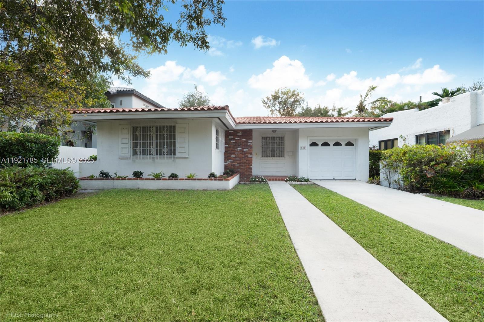 This Coral Gables residence, exceptionally located just minutes from Miracle Mile and the historic Granada Golf Course, is enveloped by a lush, mature tropical garden that elevates its classic charm. The home features clean, light-colored exterior walls and a traditional barrel-tile roof—hallmarks of timeless Coral Gables architecture. Large windows invite abundant natural light while framing soothing views of the surrounding greenery.Inside, the home offers a flexible floorplan, providing ample opportunity to tailor the space to your vision—whether you’re looking to refresh, reconfigure, or simply add your personal touches to make it your own.Outside, a winding stone pathway weaves through vibrant, layered landscaping filled with ferns, palms, bromeliads, and other South Florida natives. Towering shade trees form a natural canopy, allowing dappled sunlight to filter across the garden. The fully grown vegetation adds both beauty and privacy, creating the feeling of a secluded retreat. This tranquil, tropical setting perfectly complements the home’s character, blending indoor comfort with an inviting outdoor oasis—all in an exceptionally well-located pocket of Coral Gables.