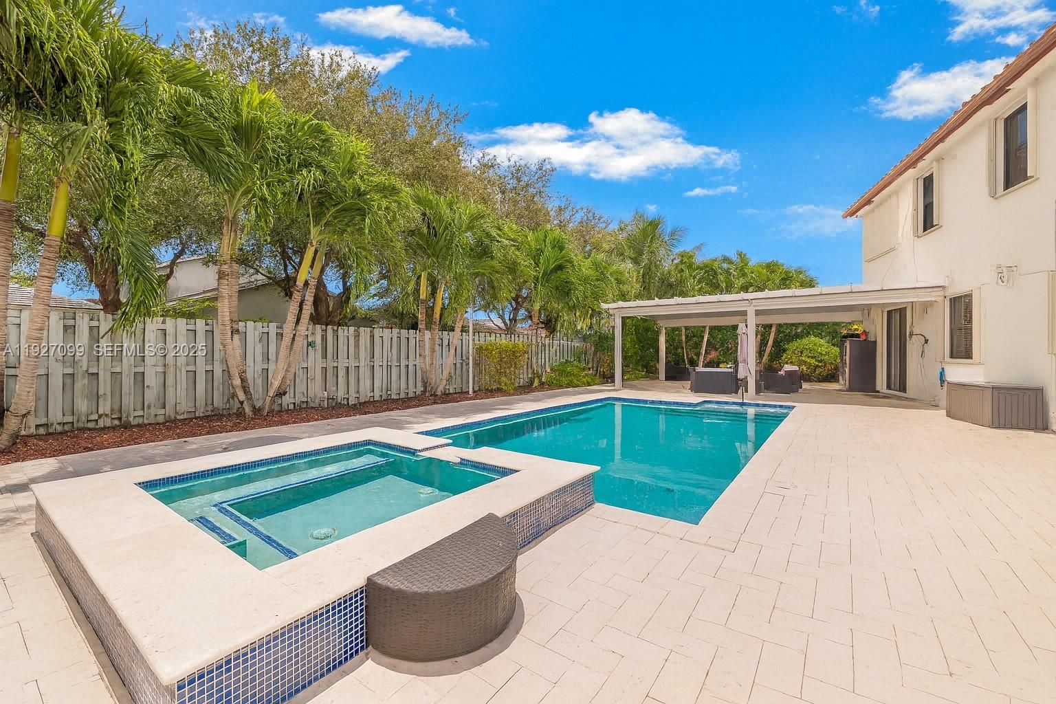 Discover the perfect blend of space, elegance, and resort-style living in this stunning two-story home set on an impressive 11,980 sq. ft. lot. Boasting a 3-car garage and an expansive driveway, this residence offers both comfort and convenience for families, entertainers, and those seeking elevated living. With 5 bedrooms, 4 bathrooms, and 4,320 sq. ft. of living area, there is truly room for everyone.Step inside to find a beautifully updated kitchen and two remodeled bathrooms, all completed in 2022 with modern finishes and thoughtful design. Wood stairs and contemporary light fixtures add a sophisticated touch, enhancing the home’s warm yet refined ambiance. The outdoor space is a true Florida oasis. Enjoy travertine flooring throughout the backyard, an aluminum terrace, and a charming wood gazebo perfect for gatherings. Relax in your private pool and Jacuzzi, equipped with colored lighting and a propane gas heater—ideal for evening dips or weekend fun. Additional upgrades include two water filtration systems, a sprinkler system, and accordion shutters throughout, ensuring comfort and peace of mind year-round.Located inside a secure gated community, residents enjoy top-tier amenities including a gym, playground, community pool, and splash water park—everything you need for a vibrant and active lifestyle. This exceptional property offers the perfect combination of luxury, functionality, and outdoor enjoyment—ready for its next owner to call home.