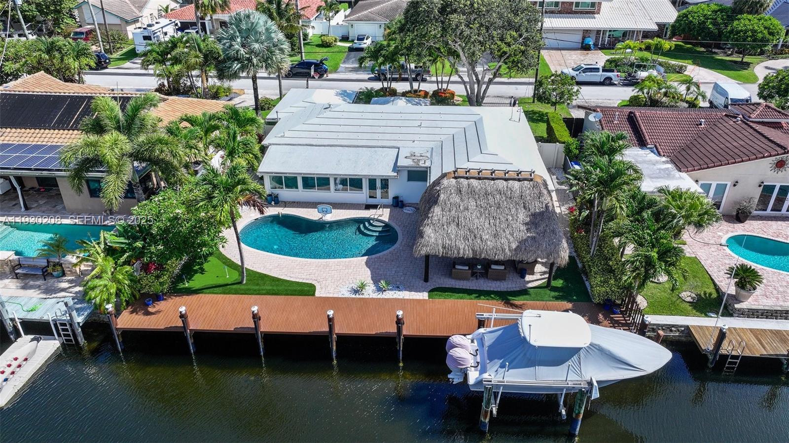 Situated on 75' ft of waterfront with deep water access and no fixed bridges! NO HOA. This stunning home in the desirable Pompano Isles community is truly a boater’s dream offering direct ocean access just minutes to the Intracoastal. The sun filled interior features an open floor plan with porcelain tile flooring throughout. The modern white kitchen boasts quartzite countertops, top-of-the-line appliances, and a gas range and oven. Enjoy peace of mind with impact windows & doors, updated plumbing & electric, and a beautifully resurfaced pool. The spacious primary suite offers serene pool views and a spa like ensuite bath with oversized dual shower and double sinks. Step outside to your private waterfront oasis featuring a newer resin dock, boat lift, tiki hut and a small golf putting green, perfect for relaxing or entertaining.
