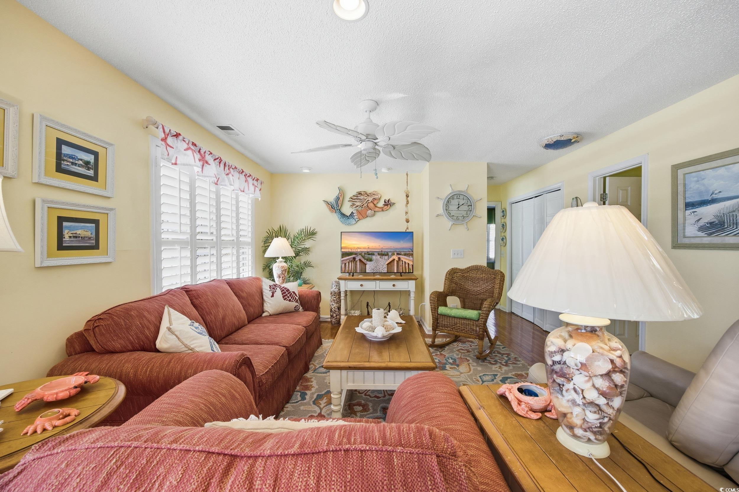 Living area featuring a textured ceiling, wood finished floors, and ceiling fan