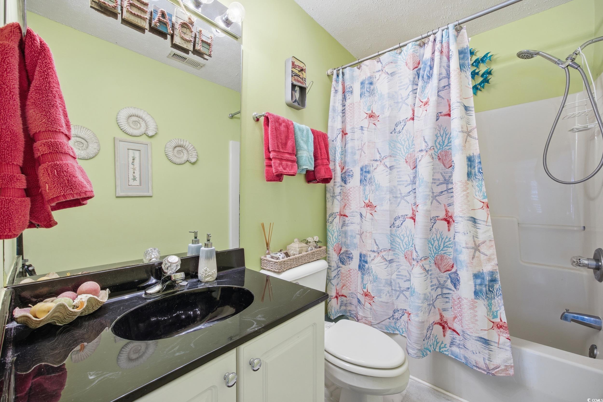 Bathroom featuring shower / bathtub combination with curtain and vanity