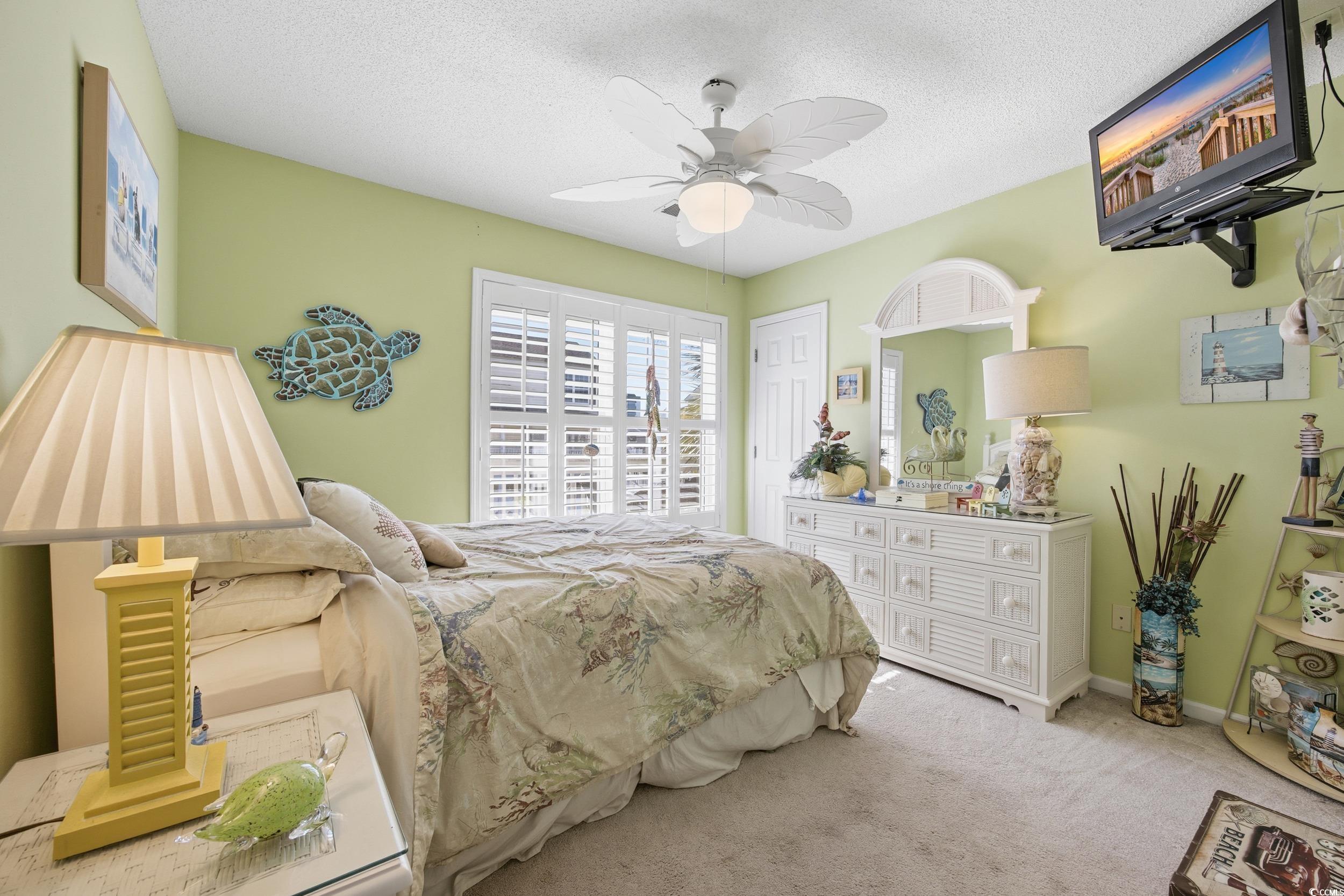Carpeted bedroom featuring a textured ceiling and a ceiling fan