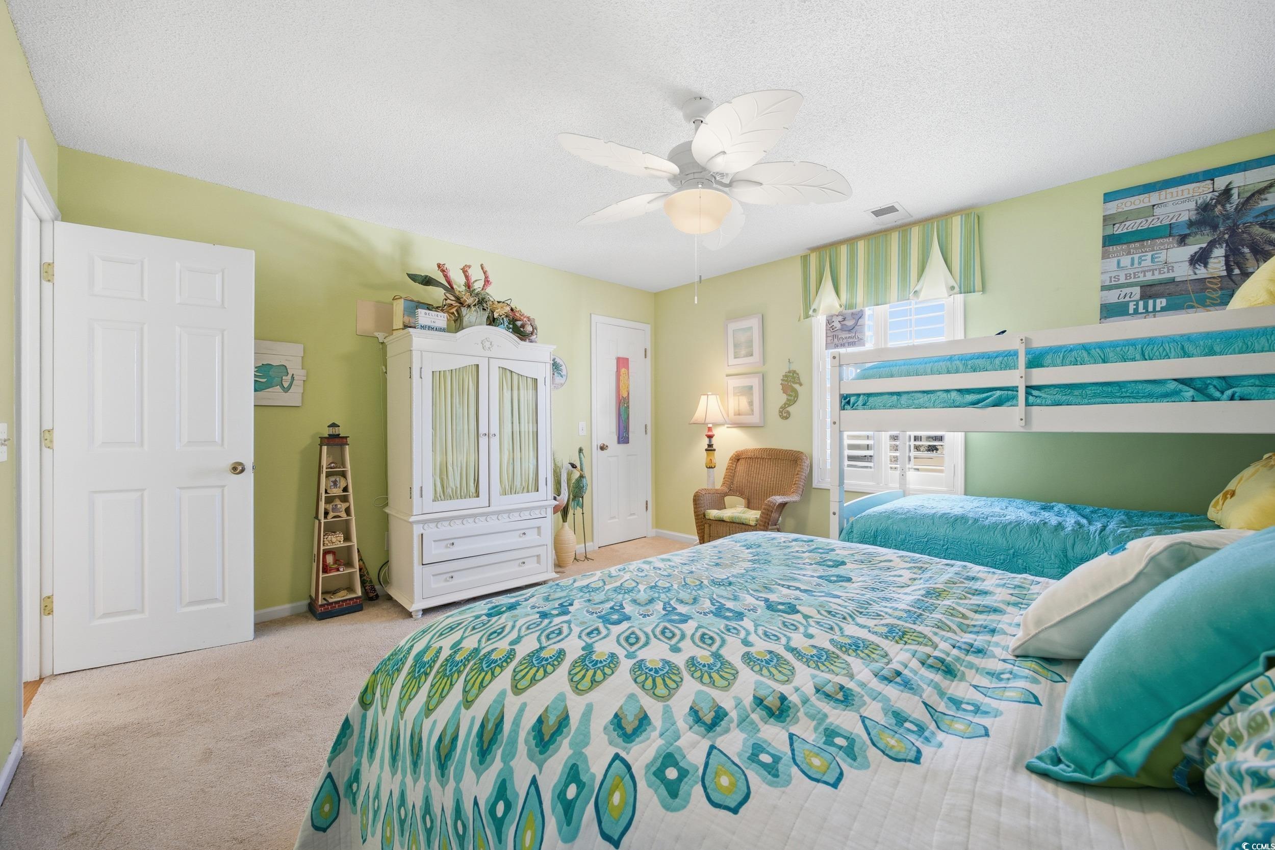 Carpeted bedroom featuring a ceiling fan and a textured ceiling