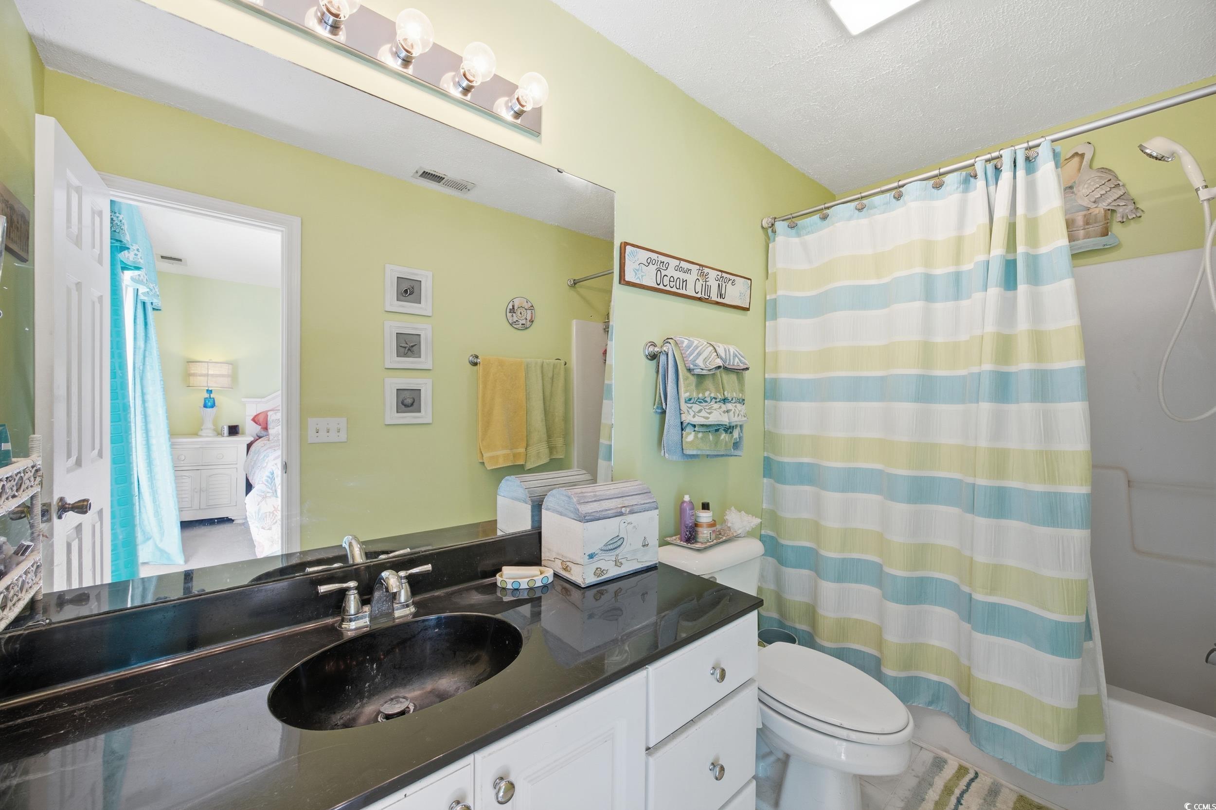 Ensuite bathroom with vanity and shower / tub combo with curtain