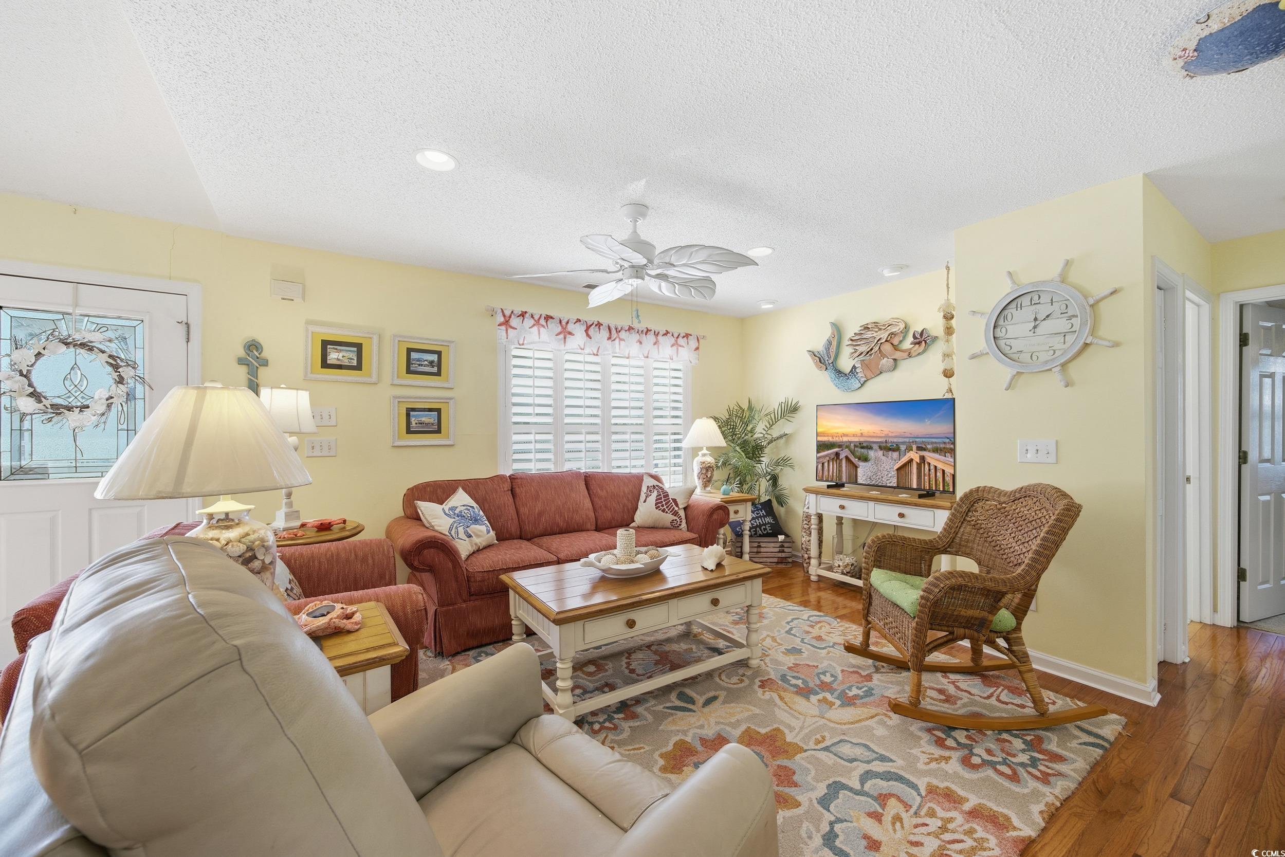 Living room with a textured ceiling, hardwood / wood-style floors, a ceiling fan, and recessed lighting