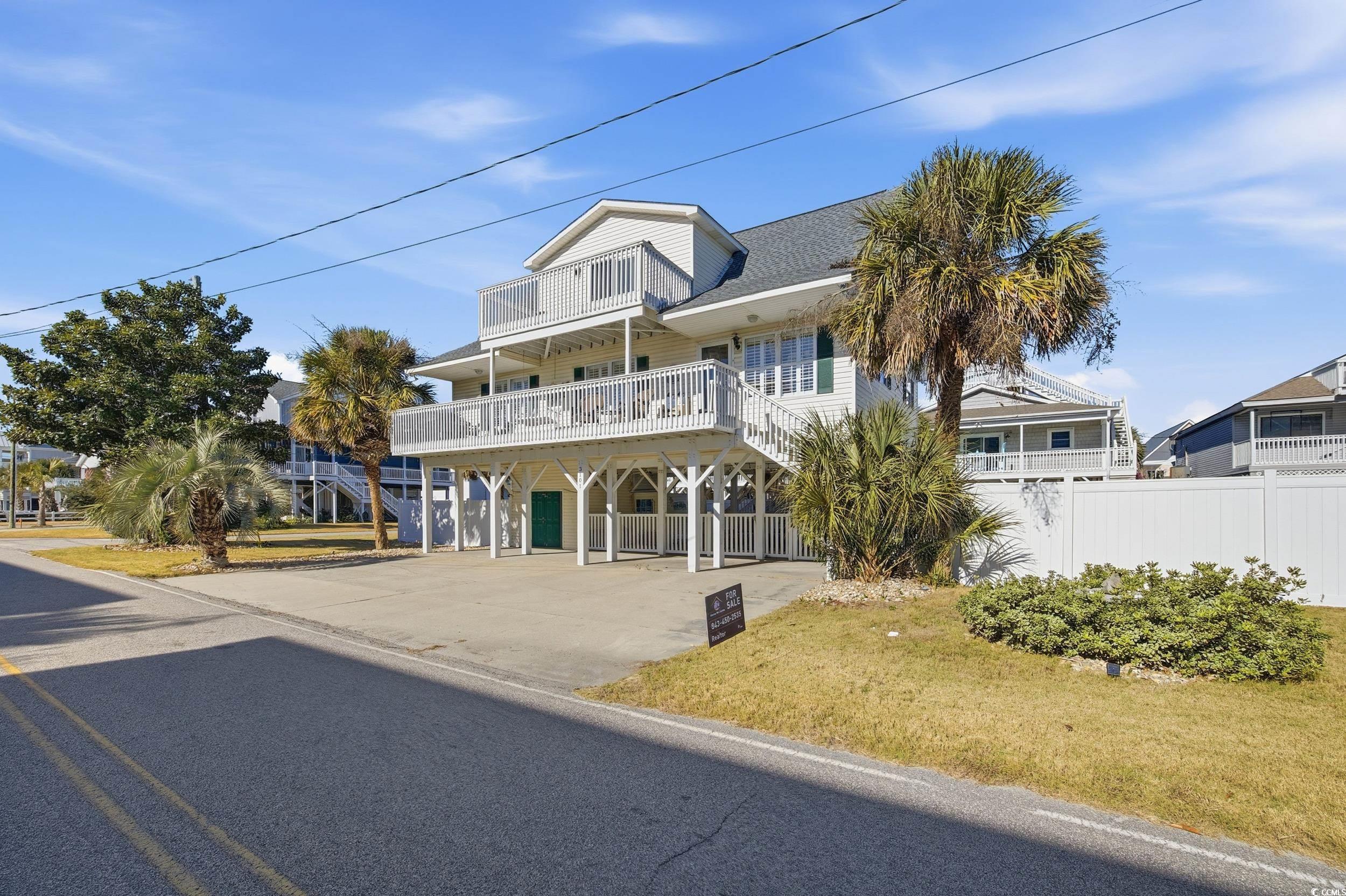 View of front of house with a carport, concrete driveway, a balcony, and a front lawn