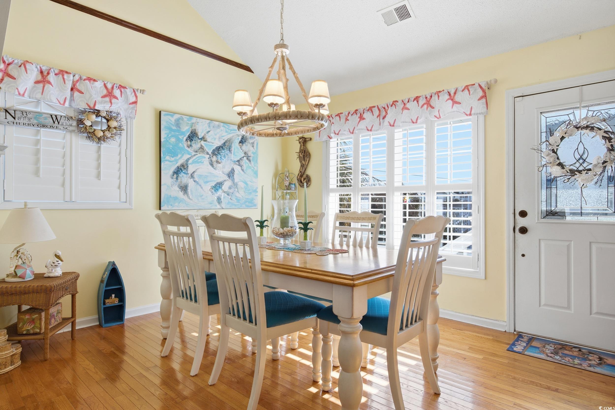 Dining area with a chandelier, light wood-style floors, and lofted ceiling