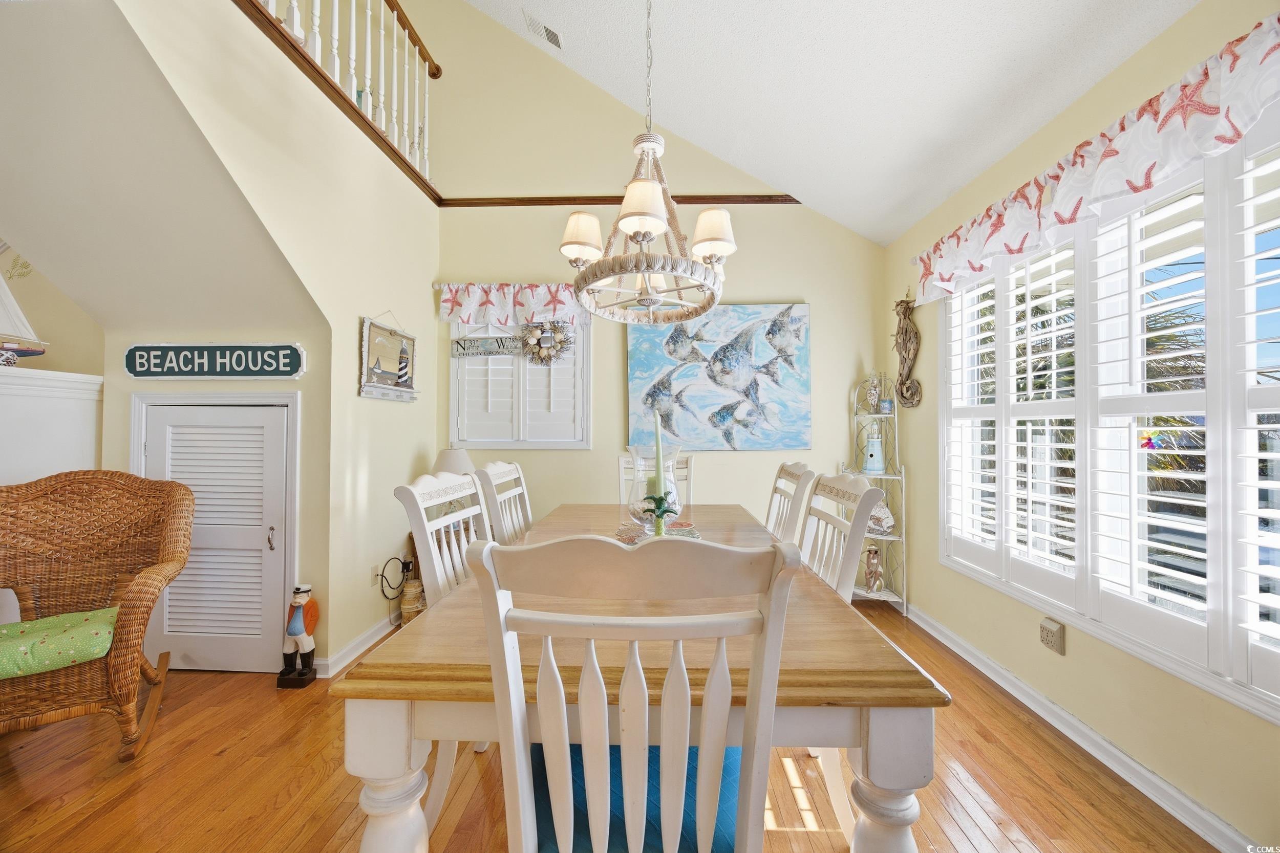 Dining room with vaulted ceiling, a chandelier, and light wood-style floors