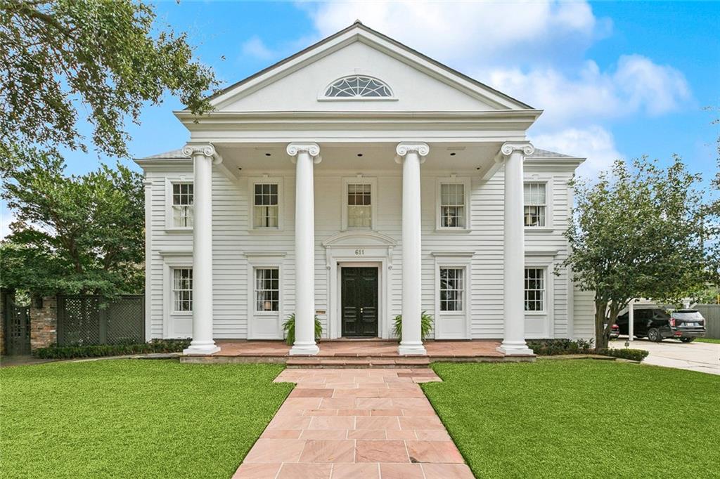 Located on oversized, walled grounds in Metairie Club Gardens, offering classic design and generous scale. Interior details include hardwood flooring, crown molding, custom millwork, decorative medallions, chandeliers, and multiple fireplaces. A formal entry opens to separate living and dining rooms designed for entertaining. The gourmet kitchen is well-appointed and connects to a breakfast area and den, with French doors leading to the courtyard and landscaped grounds. The primary suite features a sitting area and two baths. All additional bedrooms include en suite marble baths, with the option for a main-level primary suite in the den overlooking the back yard. A finished third floor adds flexible living space. Laundry rooms on both levels. Outdoor areas include a manicured courtyard and generous parking, including a three-car carport. New fence. A distinctive property in Metairie Club Gardens.