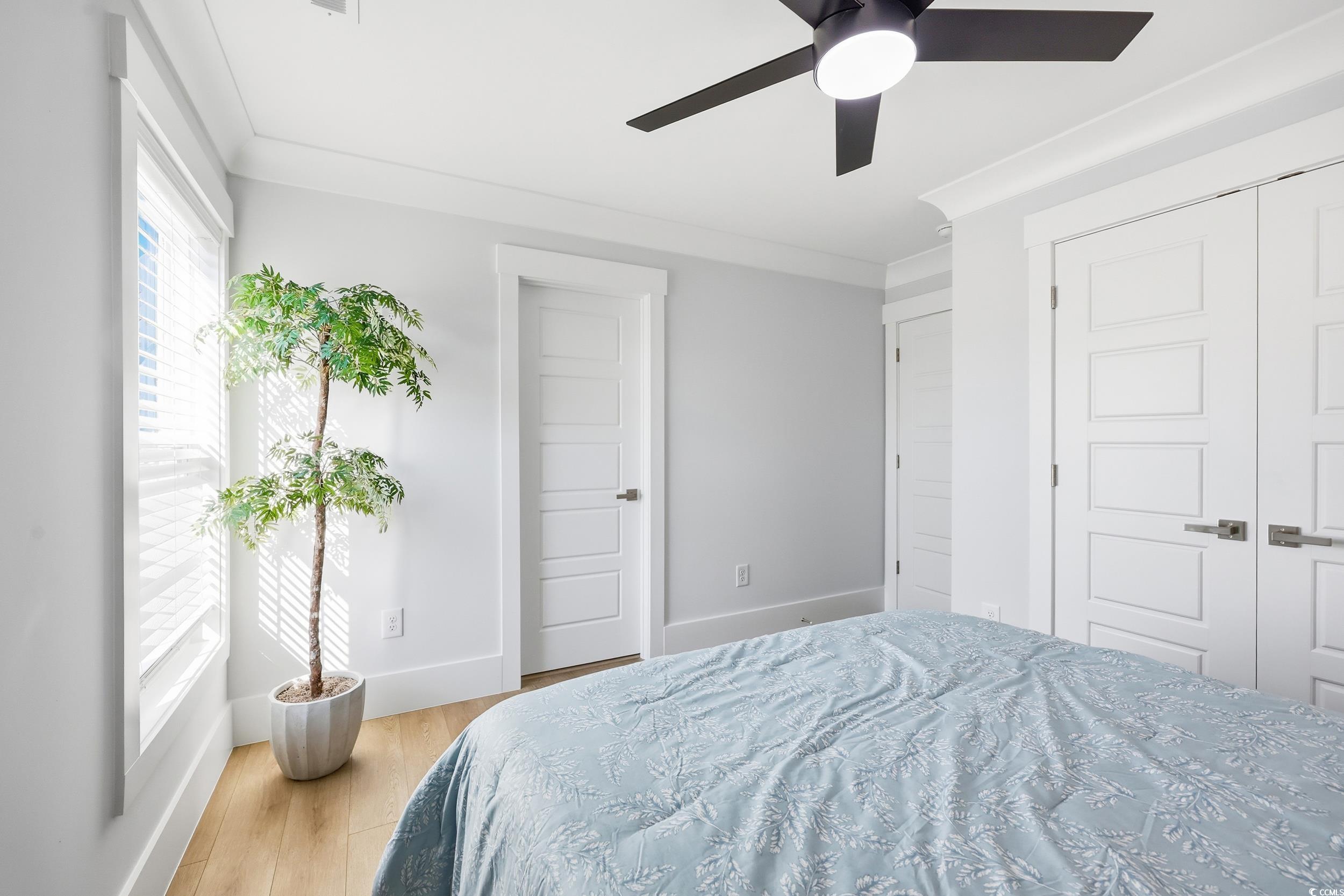 Bedroom with ornamental molding, light wood-style floors, and a ceiling fan