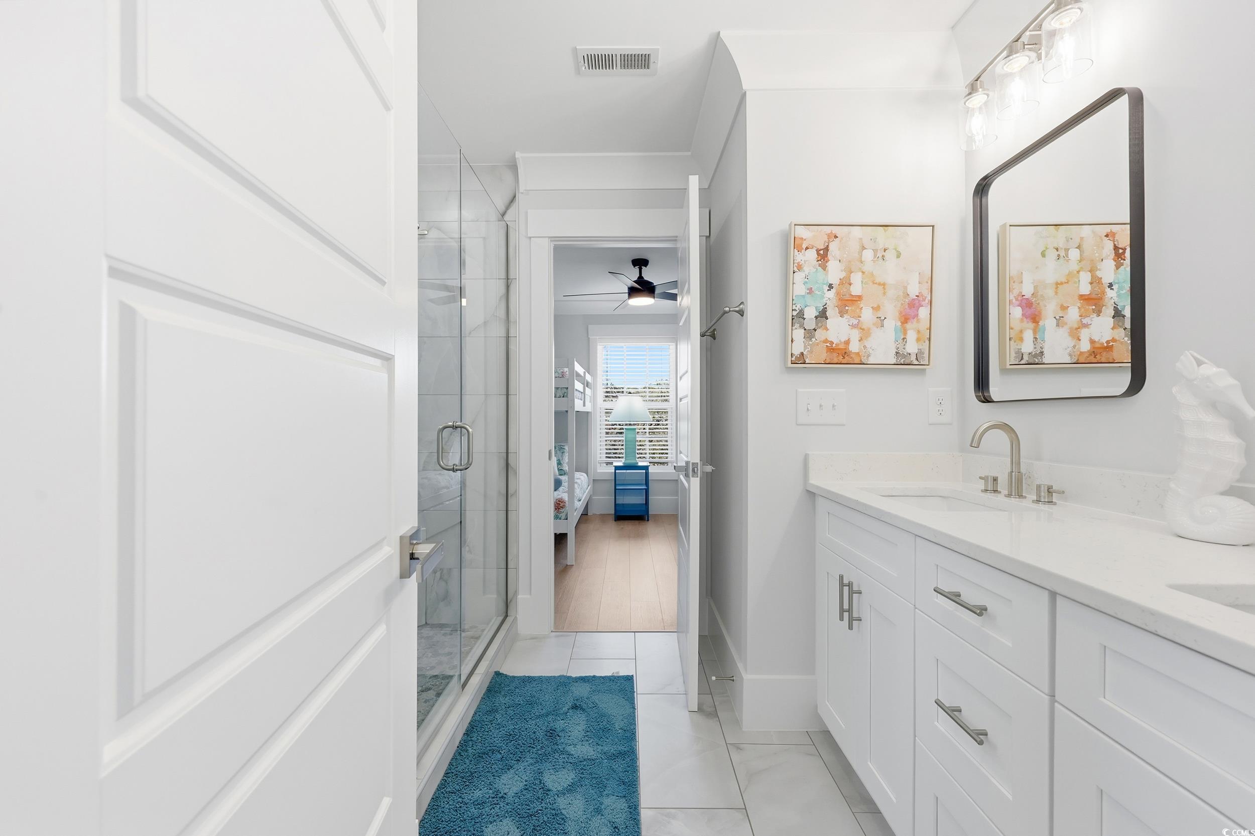 Ensuite bathroom with double vanity, ceiling fan, and a stall shower