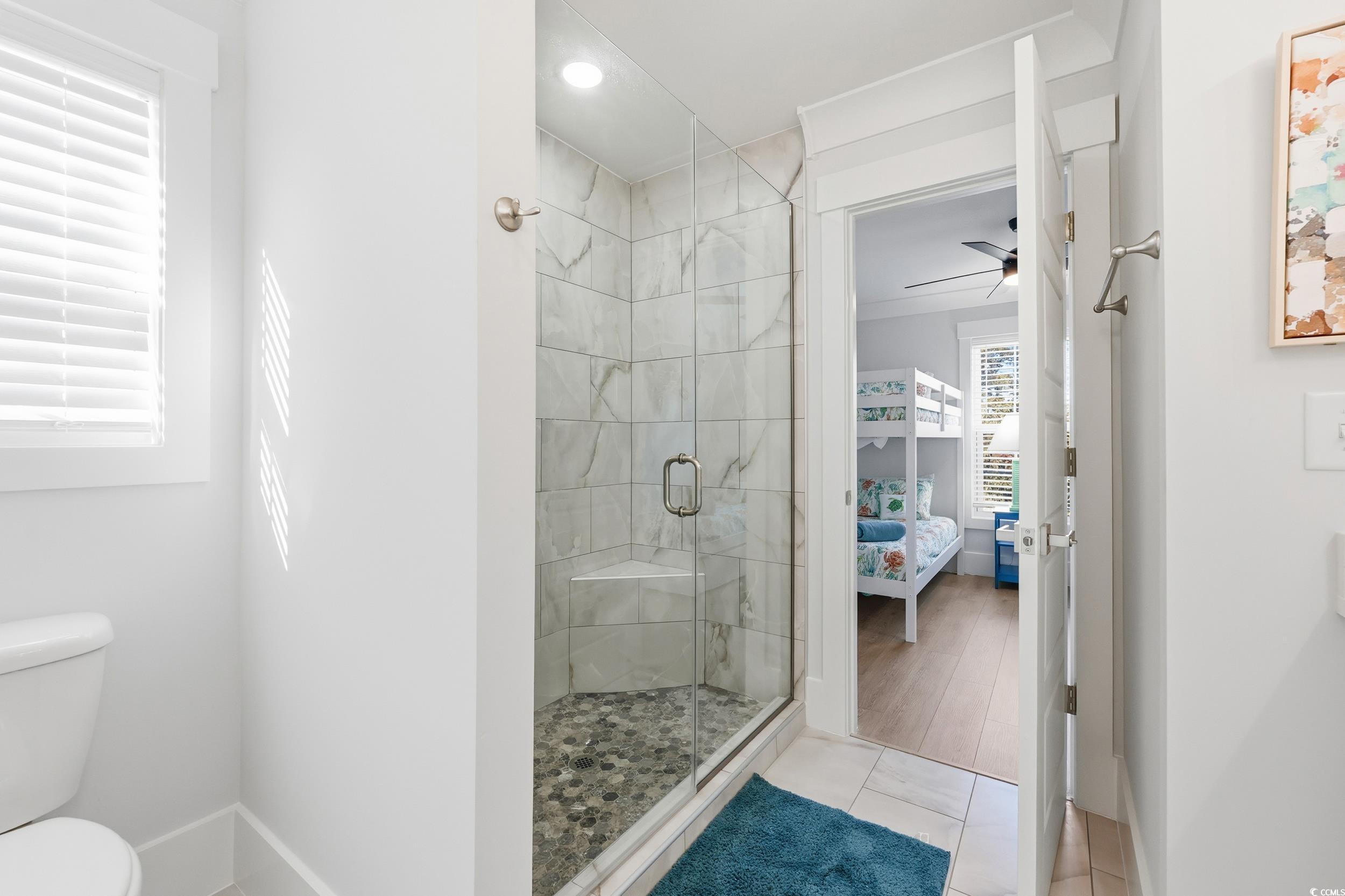 Ensuite bathroom featuring a stall shower, a ceiling fan, and light tile patterned floors